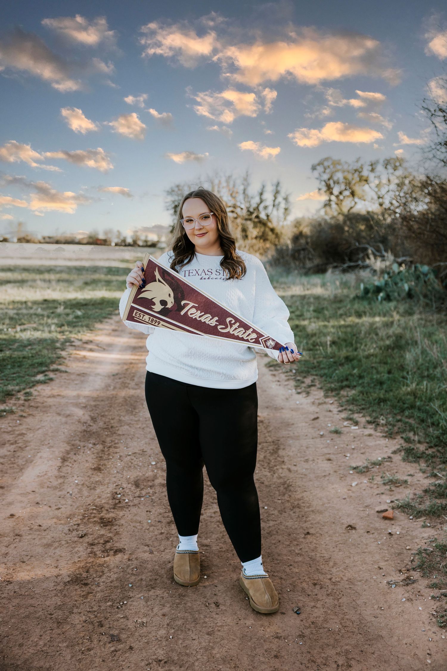 high school senior girl in college sweater at golden hour in Buffalo Gap