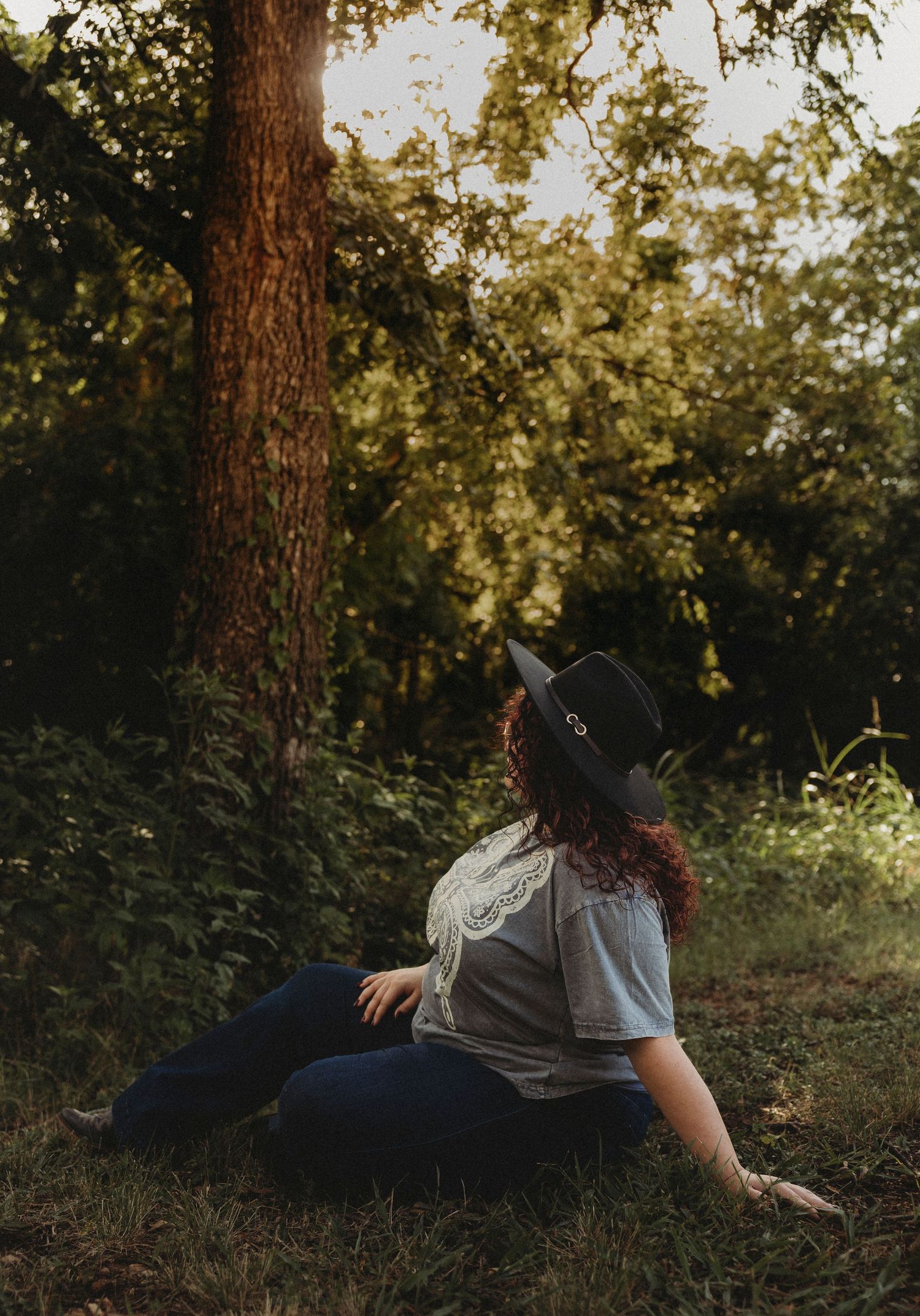 Jim Ned High School Class of 2027 senior sitting beneath a tree during a golden hour outdoor senior portrait session in Abilene, Texas.