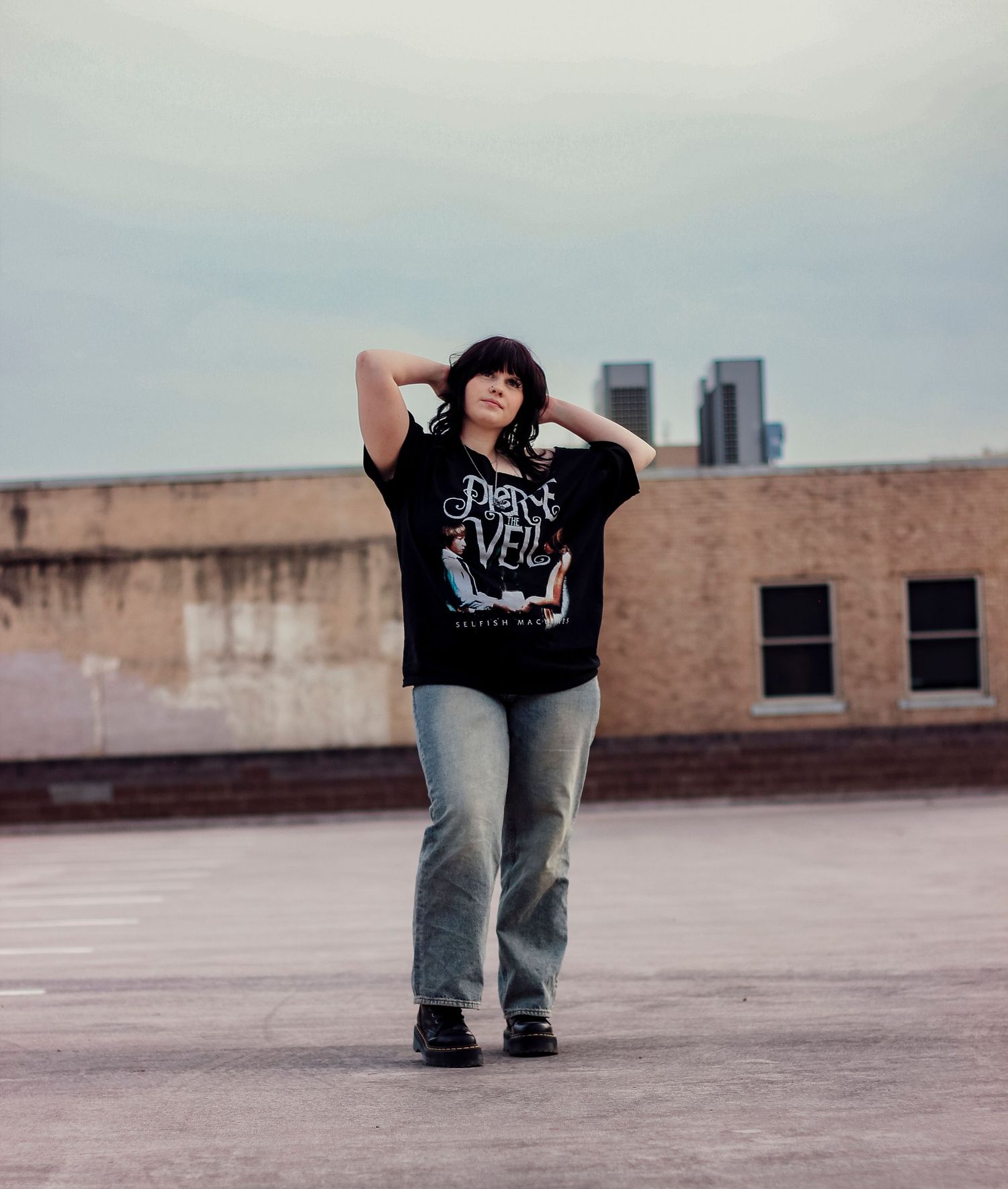Urban creative portrait session in Abilene TX featuring a subject standing on a rooftop with city buildings in the background