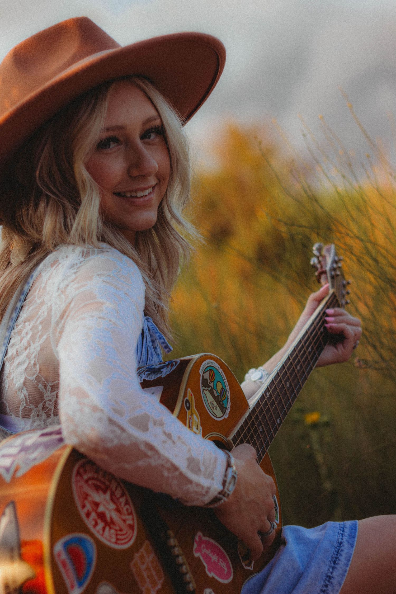 Senior portrait session in Abilene TX featuring a high school senior playing guitar with warm, golden light and natural styling