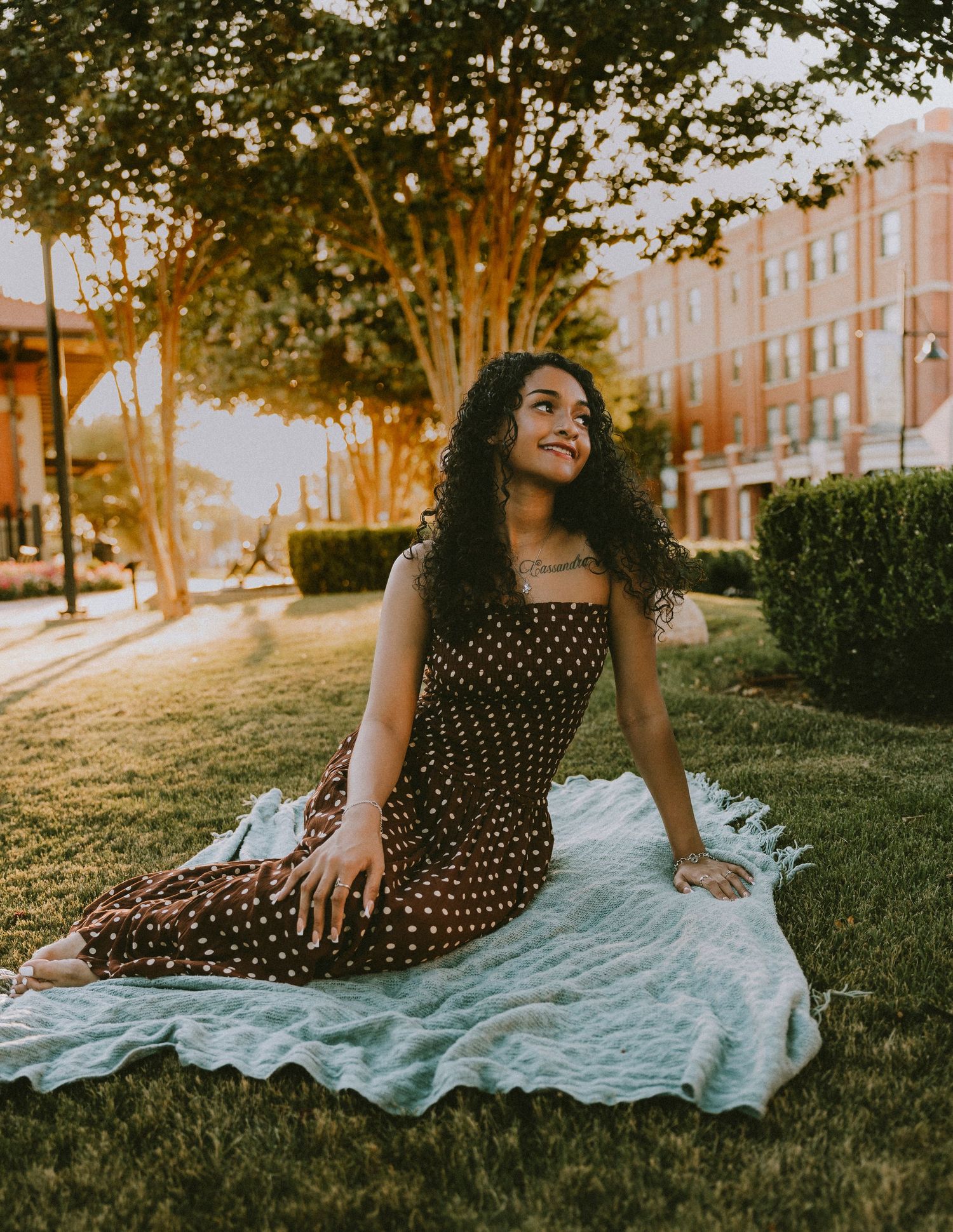 Senior girl lying on a blanket in downtown Abilene during a golden hour Cooper High School senior portrait session.