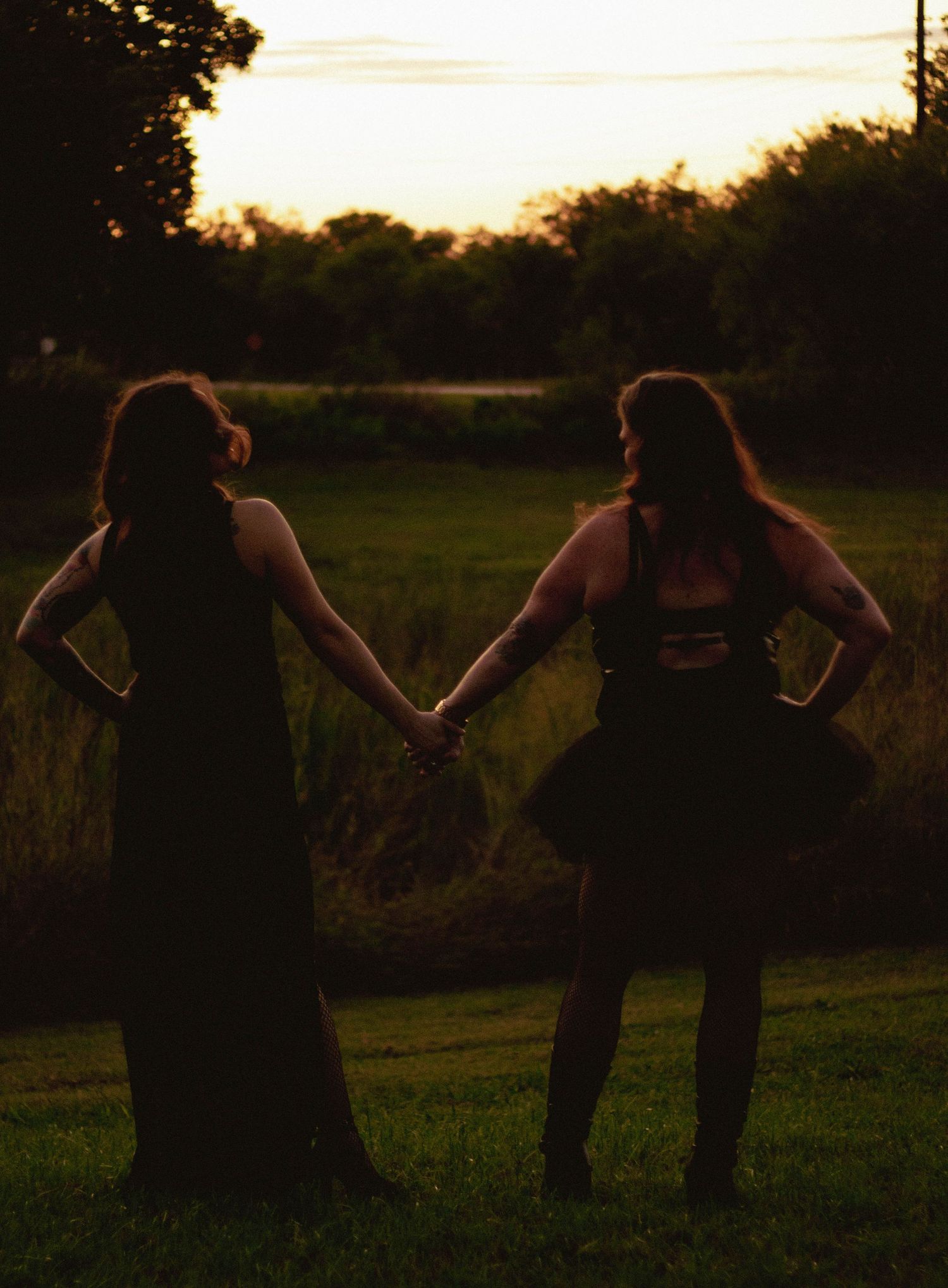 Spooky creative portrait session in Abilene TX with two women holding hands at sunset in an open field