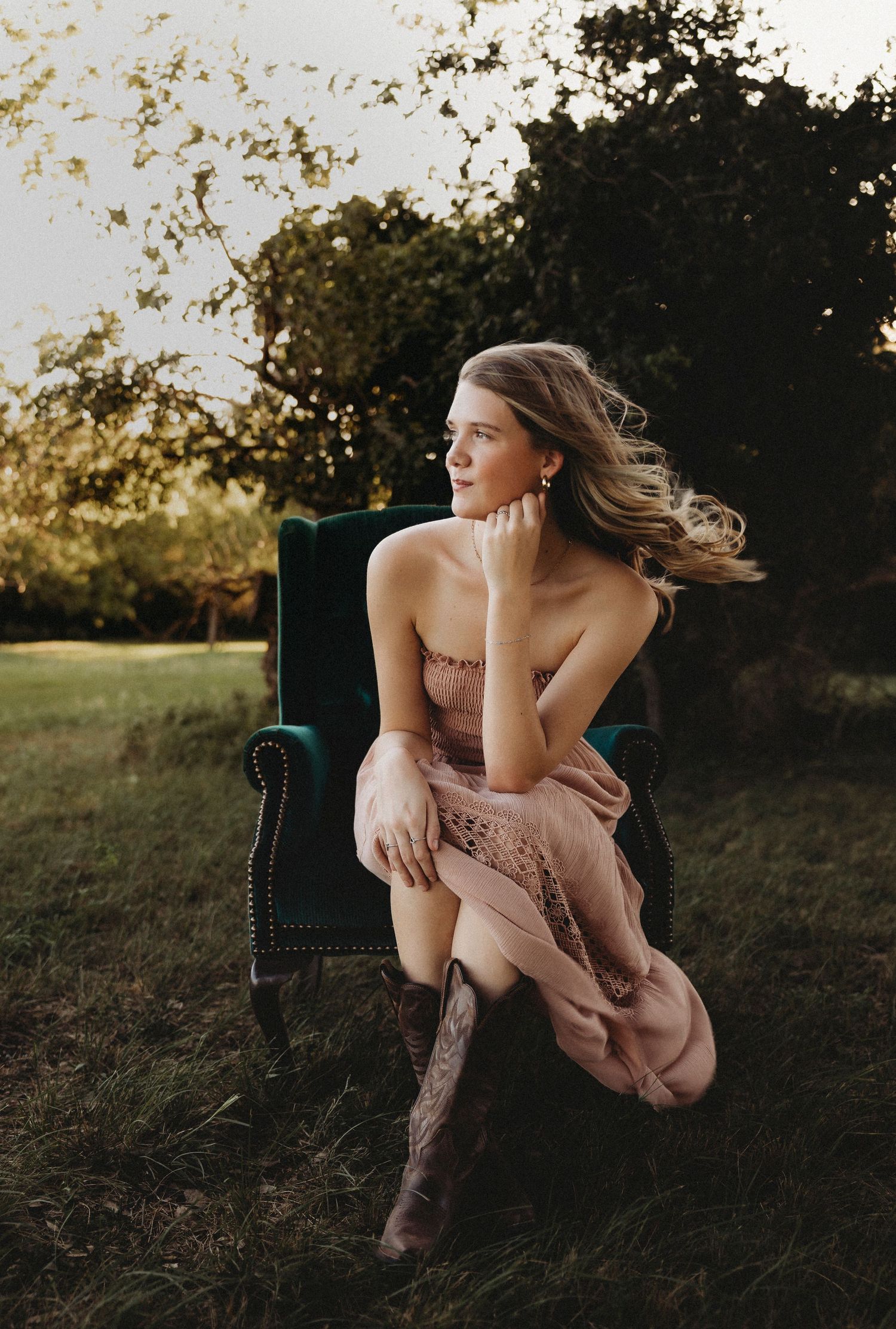 High school senior sitting outside as her hair catches the golden sunset light during an outdoor senior session in Abilene, Texas