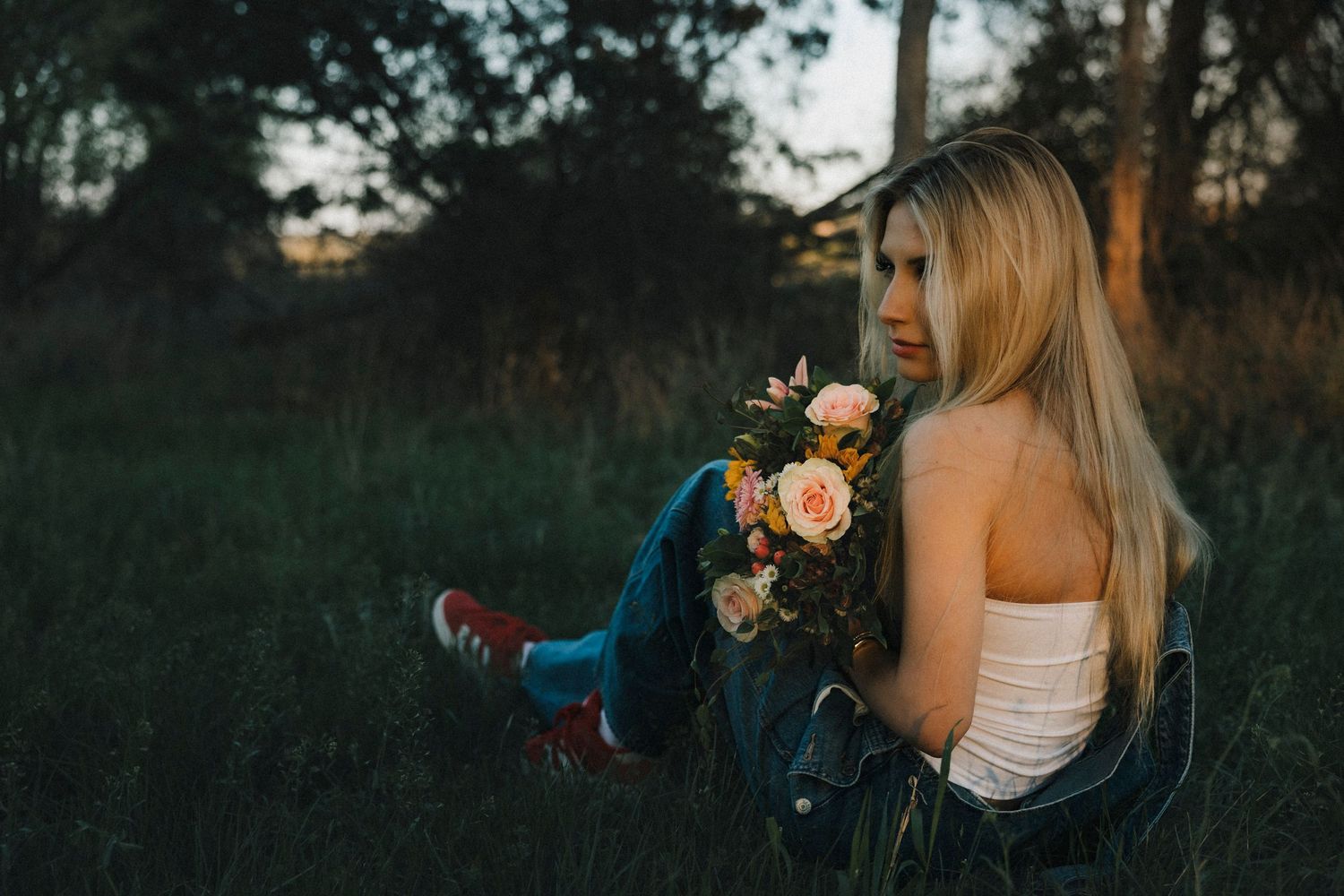 Creative senior portrait of blonde high school senior holding flowers during sunset photos in Abilene, Texas.