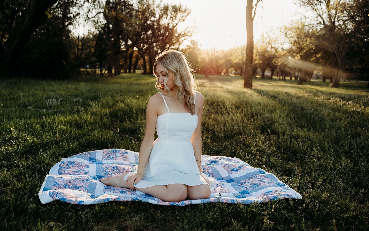 Senior photoshoot in Abilene, TX at sunset sitting on a quilt