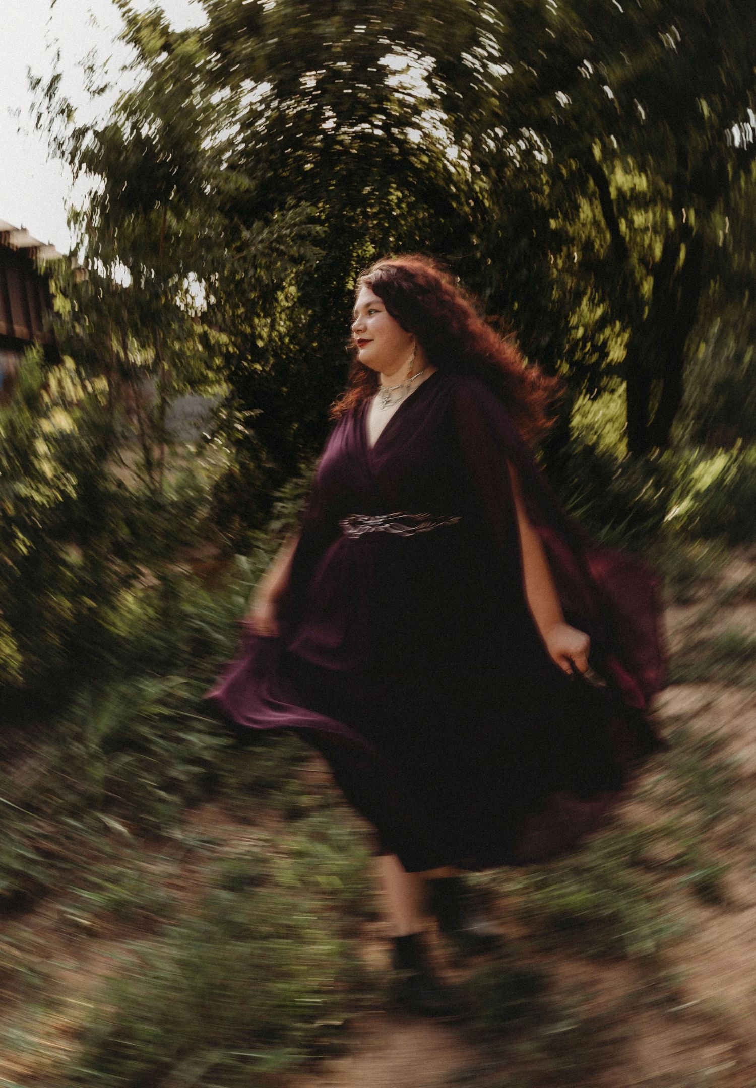 Outdoor portrait of a Jim Ned High School senior in a flowing plum dress during a whimsical golden hour senior session in Abilene, Texas.