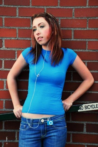 High school senior portrait against a brick wall with casual Y2K style and headphones