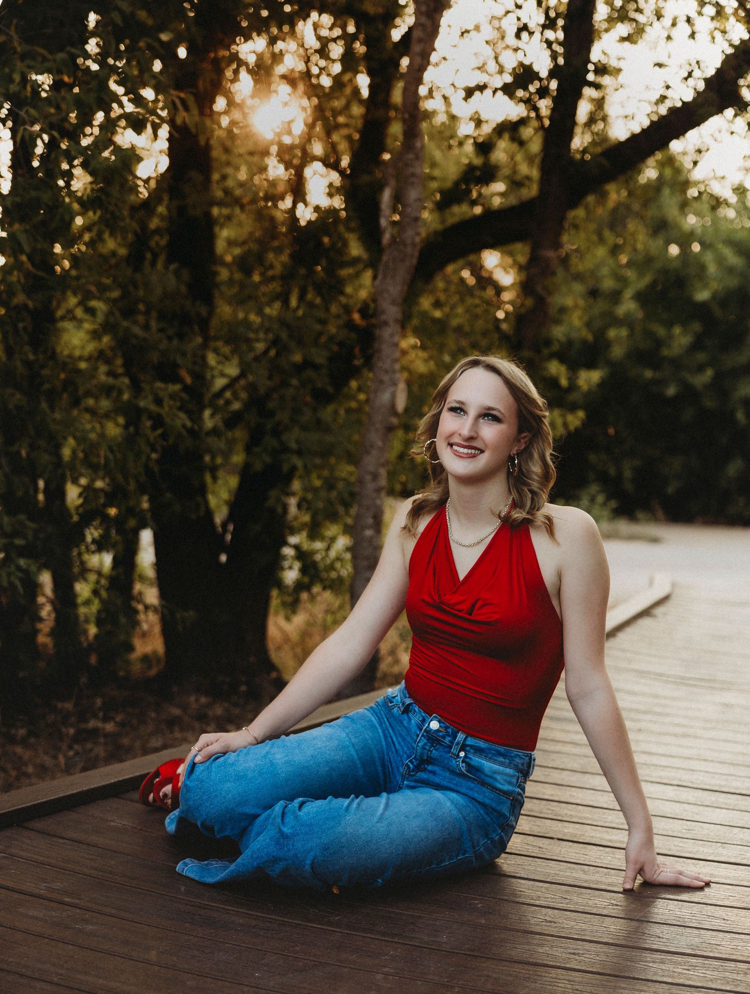 Class of 2027 senior smiling while seated on a wooden boardwalk during a natural light senior portrait session in Abilene, Texas.