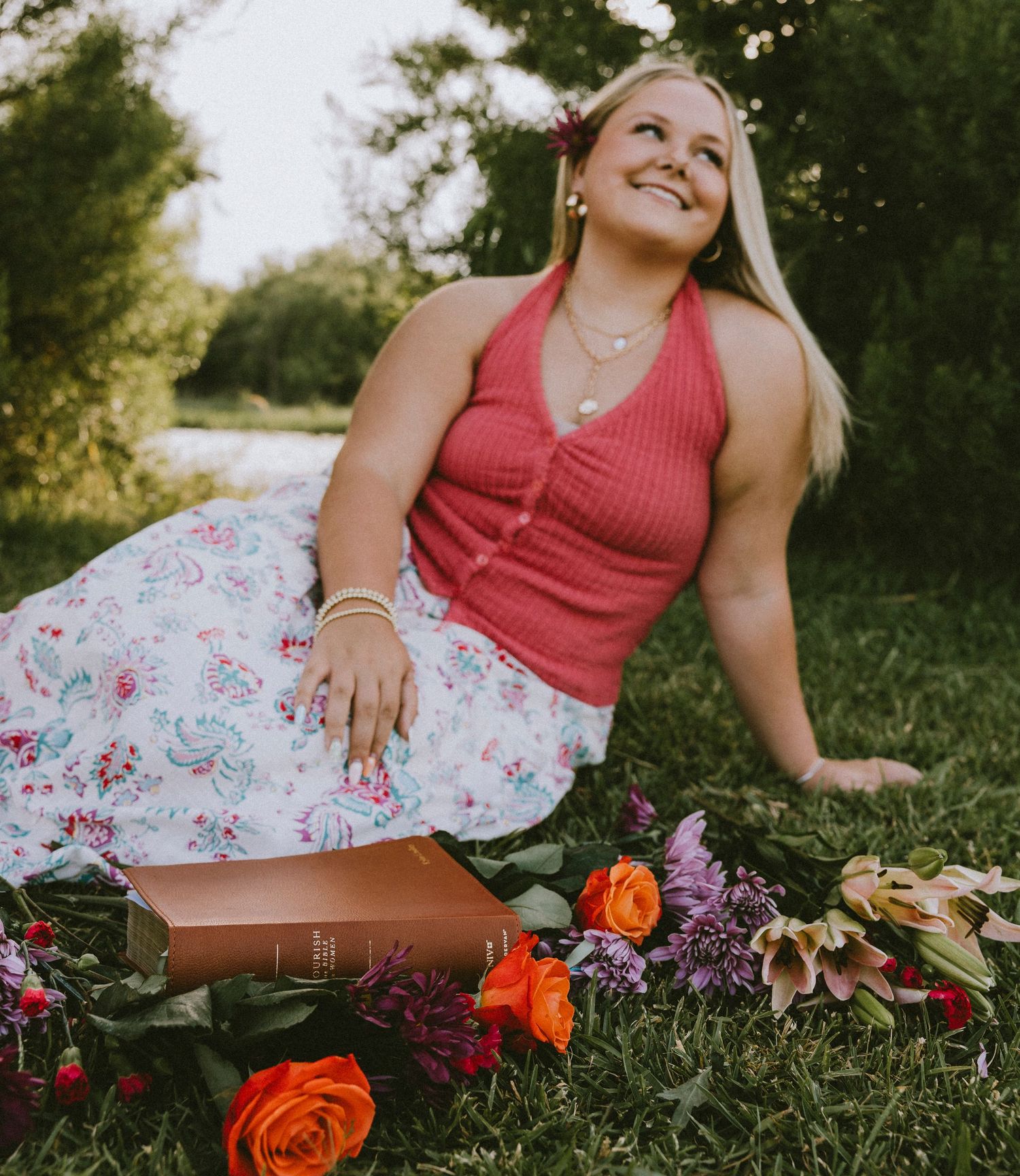 Outdoor senior portraits of a smiling high school senior sitting beside colorful flowers during a senior photos session in Abilene, Texas.