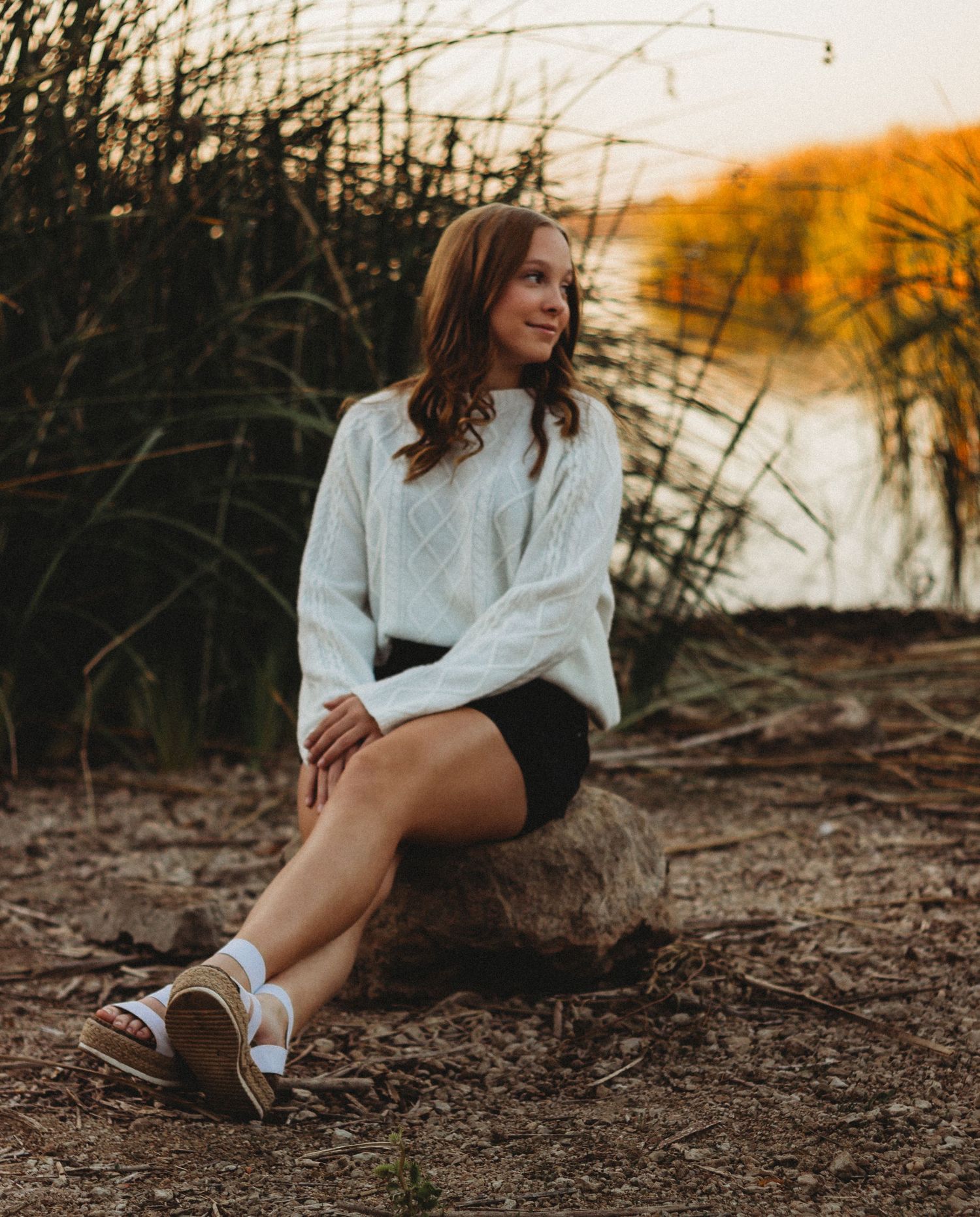 Senior girl sitting by lake during golden hour senior session in Abilene TX