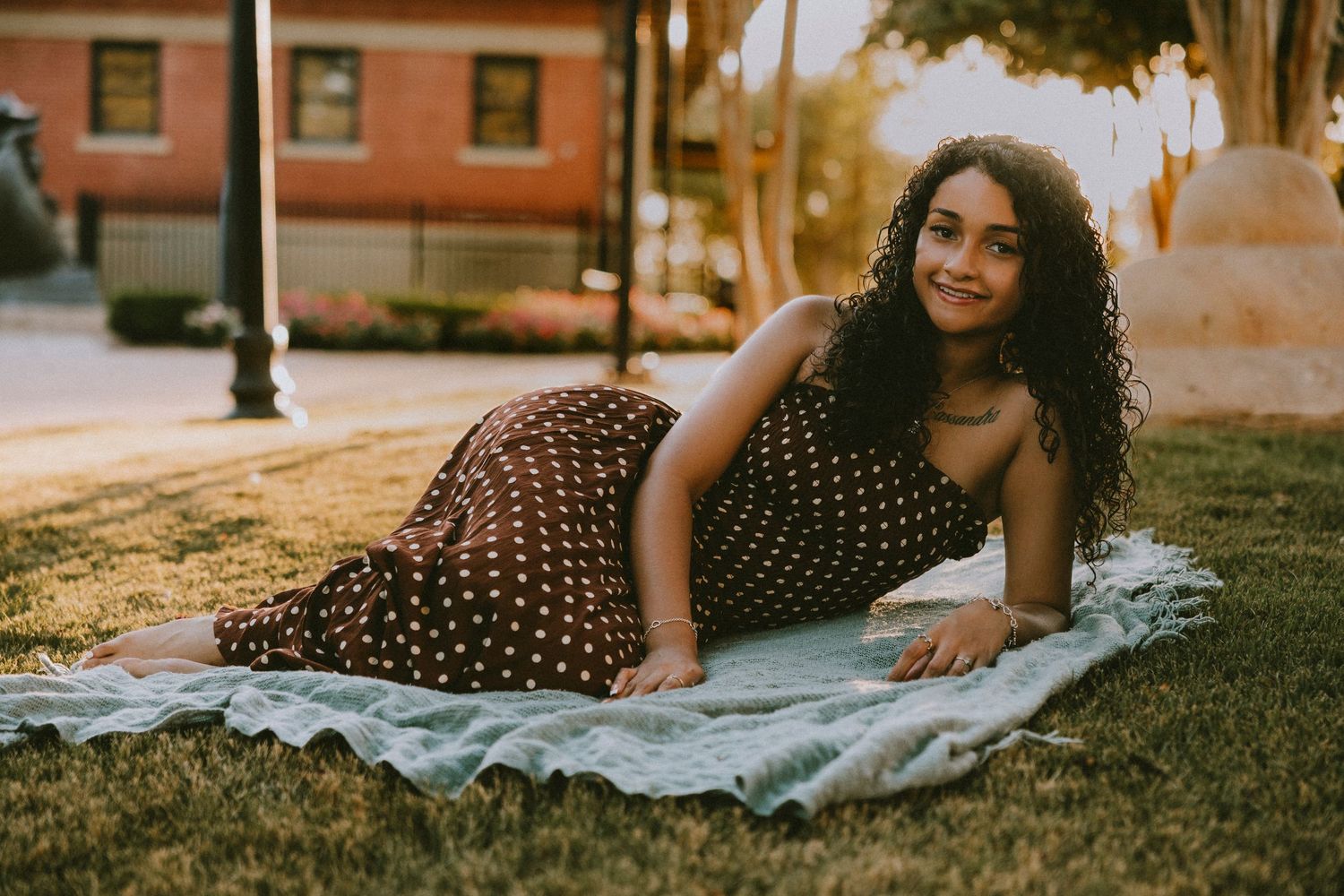 Senior girl lying on a blanket in downtown Abilene during a golden hour Cooper High School senior portrait session.
