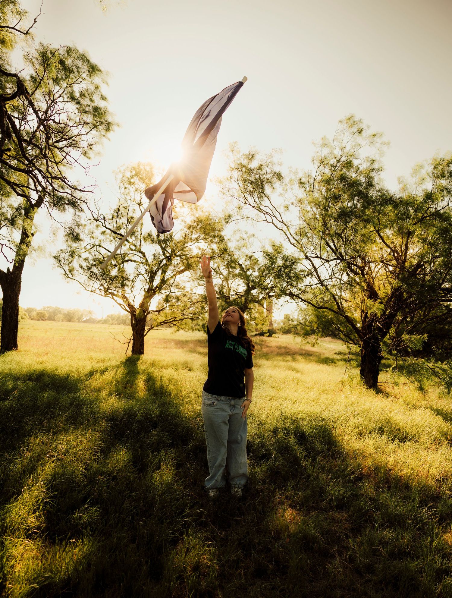Senior portrait in a golden field at sunset in Abilene, TX with warm, cinematic lighting