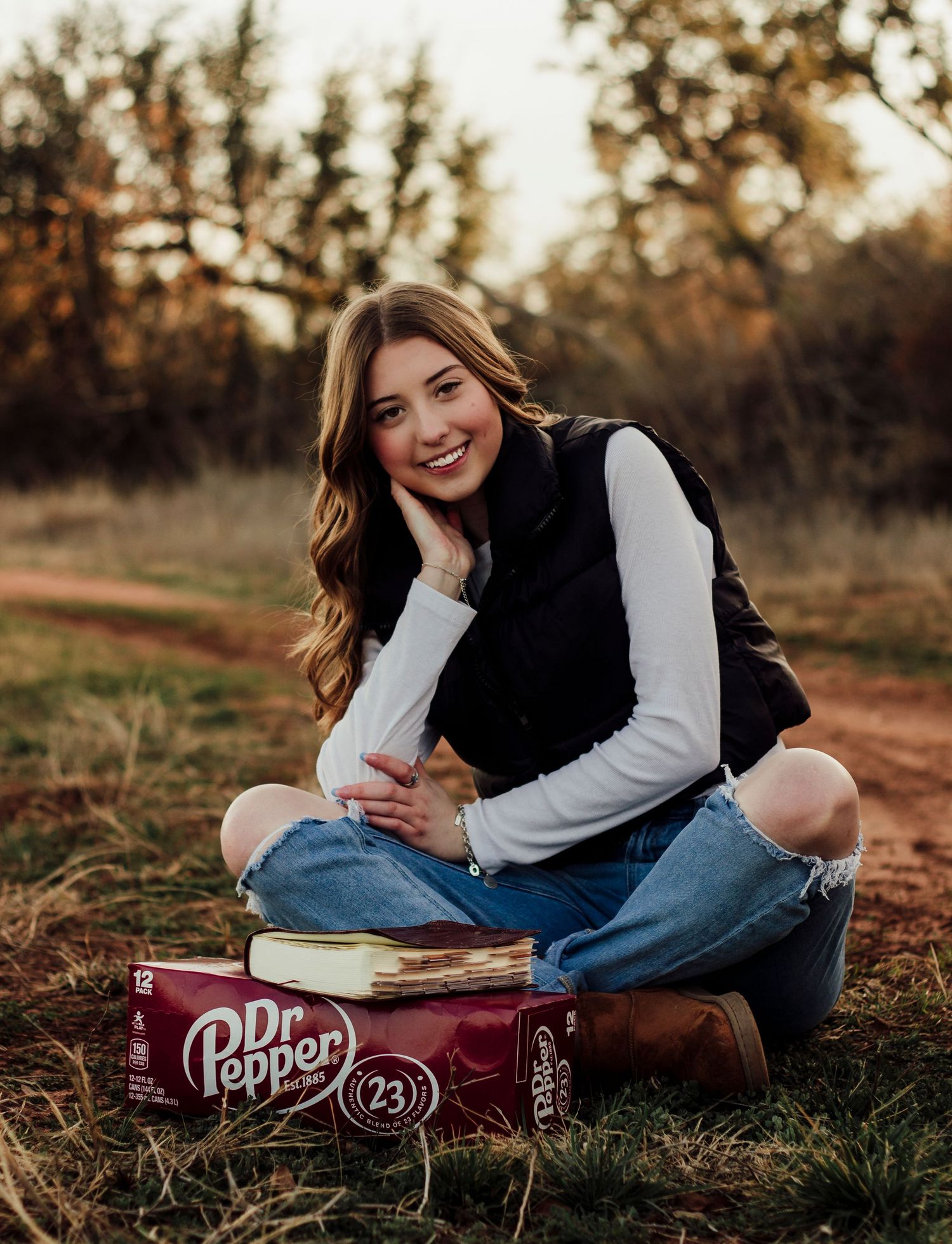 Abilene TX senior photographer capturing Texas senior photos of a high school senior sitting outdoors at golden hour holding a Dr Pepper