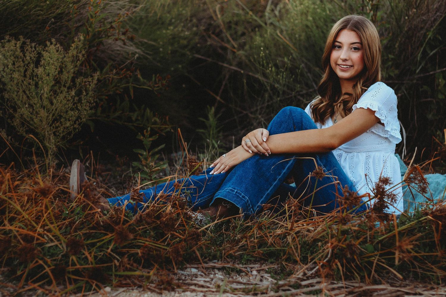 Natural senior portrait session in Abilene TX featuring a high school senior seated outdoors with relaxed posing and soft light