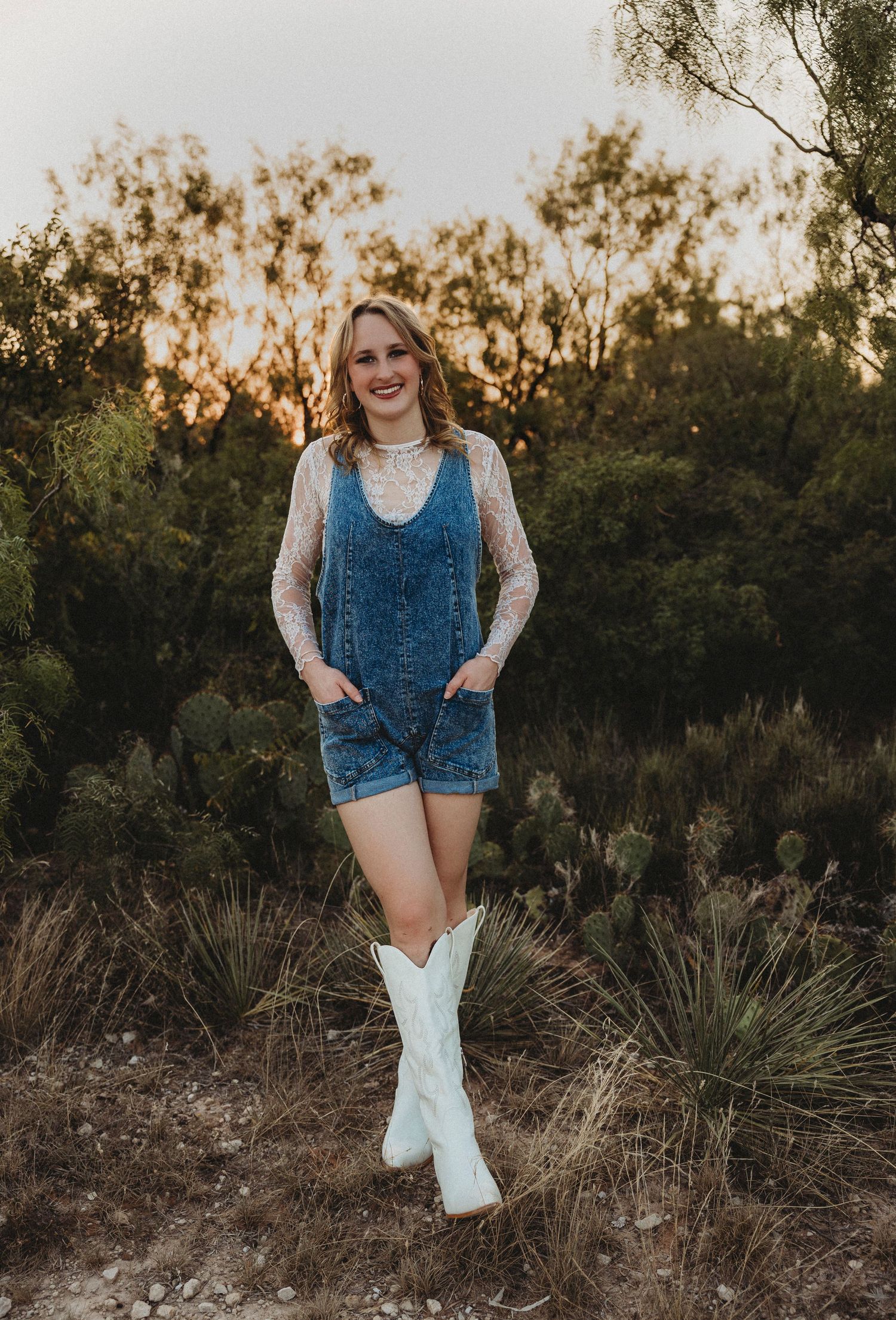 Class of 2027 senior standing among native grasses during a warm golden hour senior photography session in Abilene, Texas.