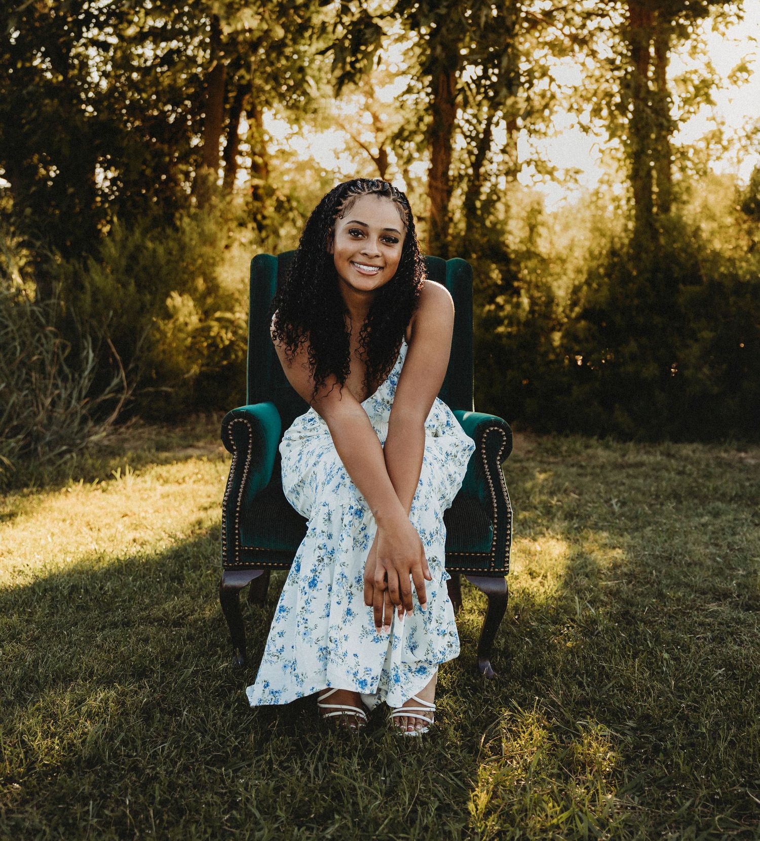 Class of 2027 Cooper High School senior smiling while seated in a vintage green wingback chair during an outdoor portrait session in Abilene