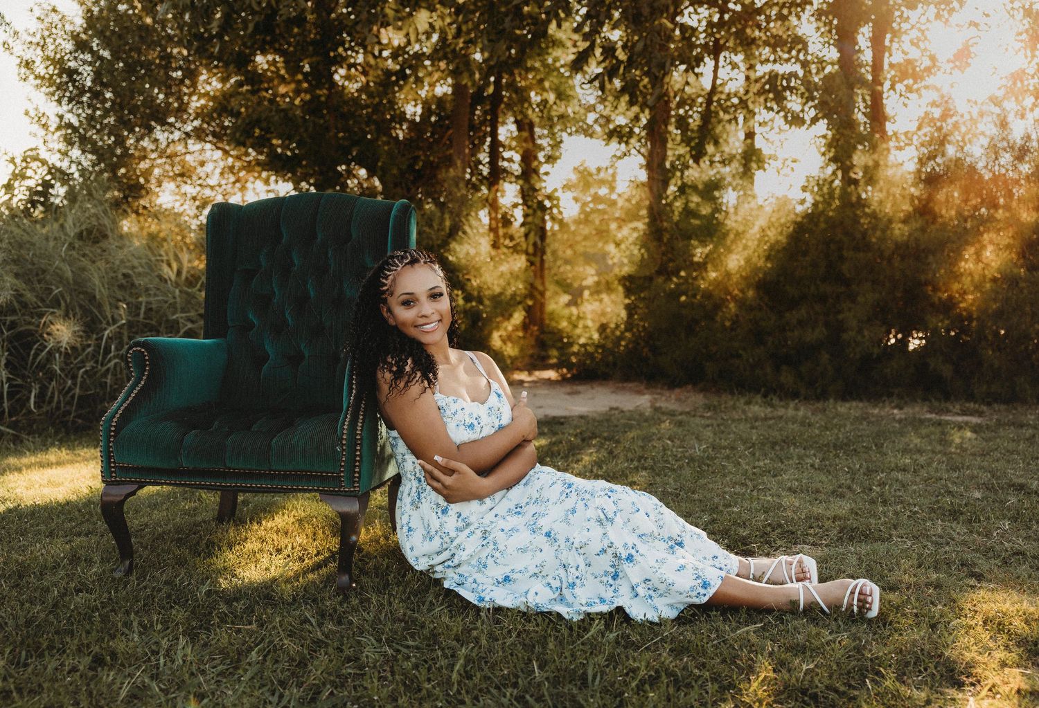 Cooper High School senior sitting beside a vintage green velvet chair during a golden hour outdoor mini session in Abilene, Texas.