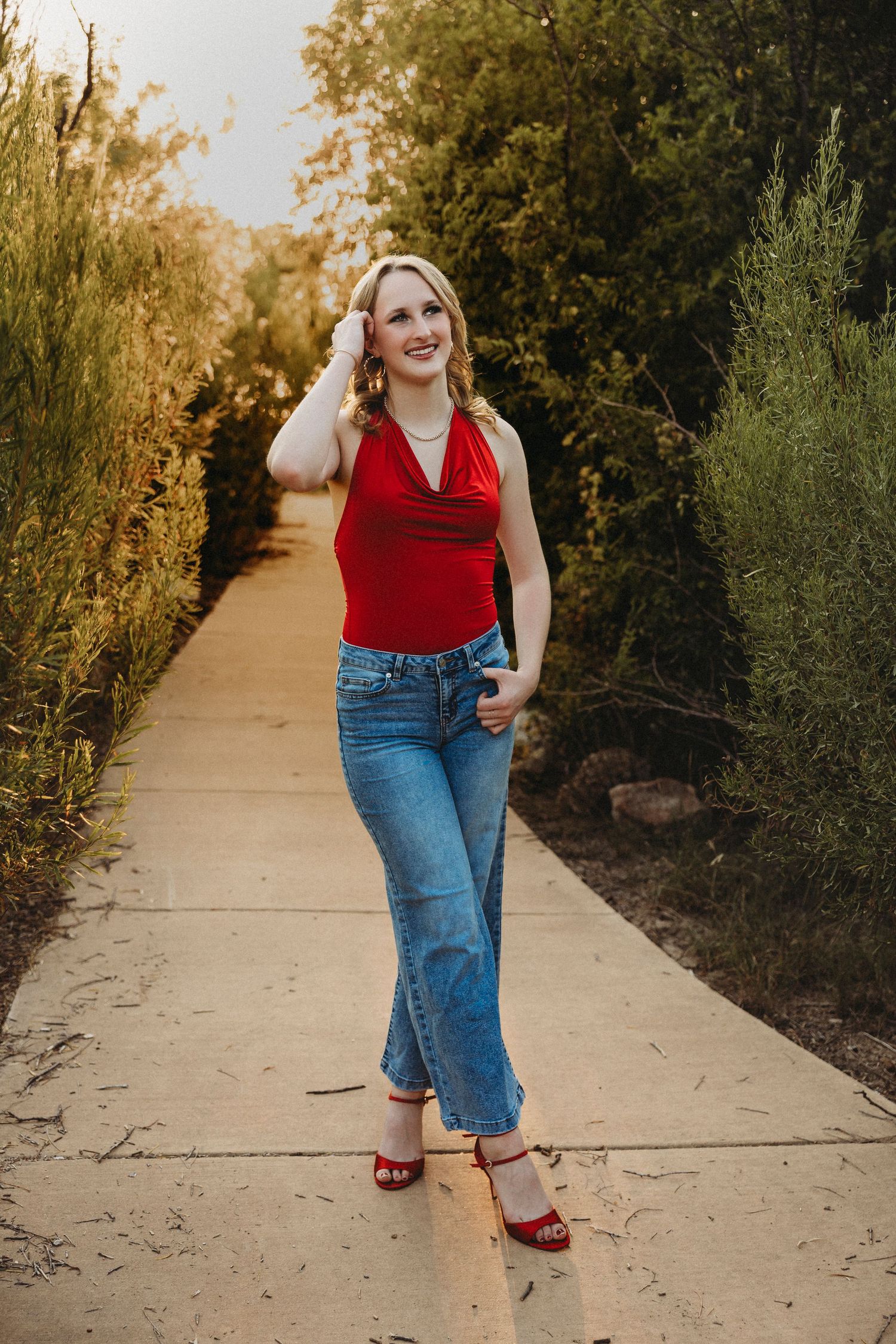Class of 2027 senior walking along a tree-lined pathway during a warm golden hour senior photography session in Abilene, Texas.