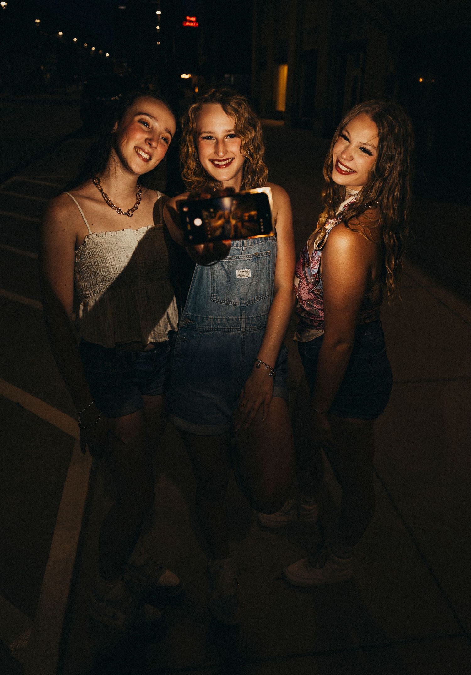 Three senior girls smiling together during a nighttime bestie photo session