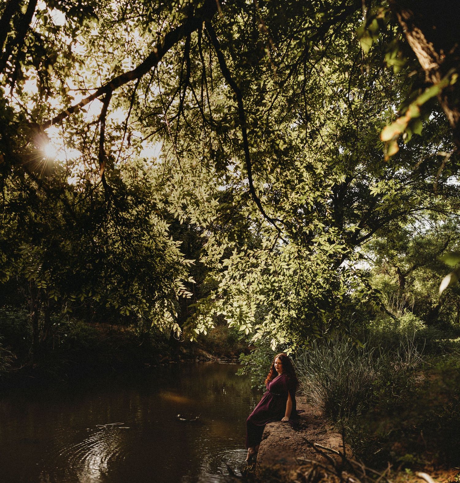 Outdoor senior portrait of a Class of 2027 senior sitting beside a peaceful creek during a golden hour senior photos session in Abilene, Te