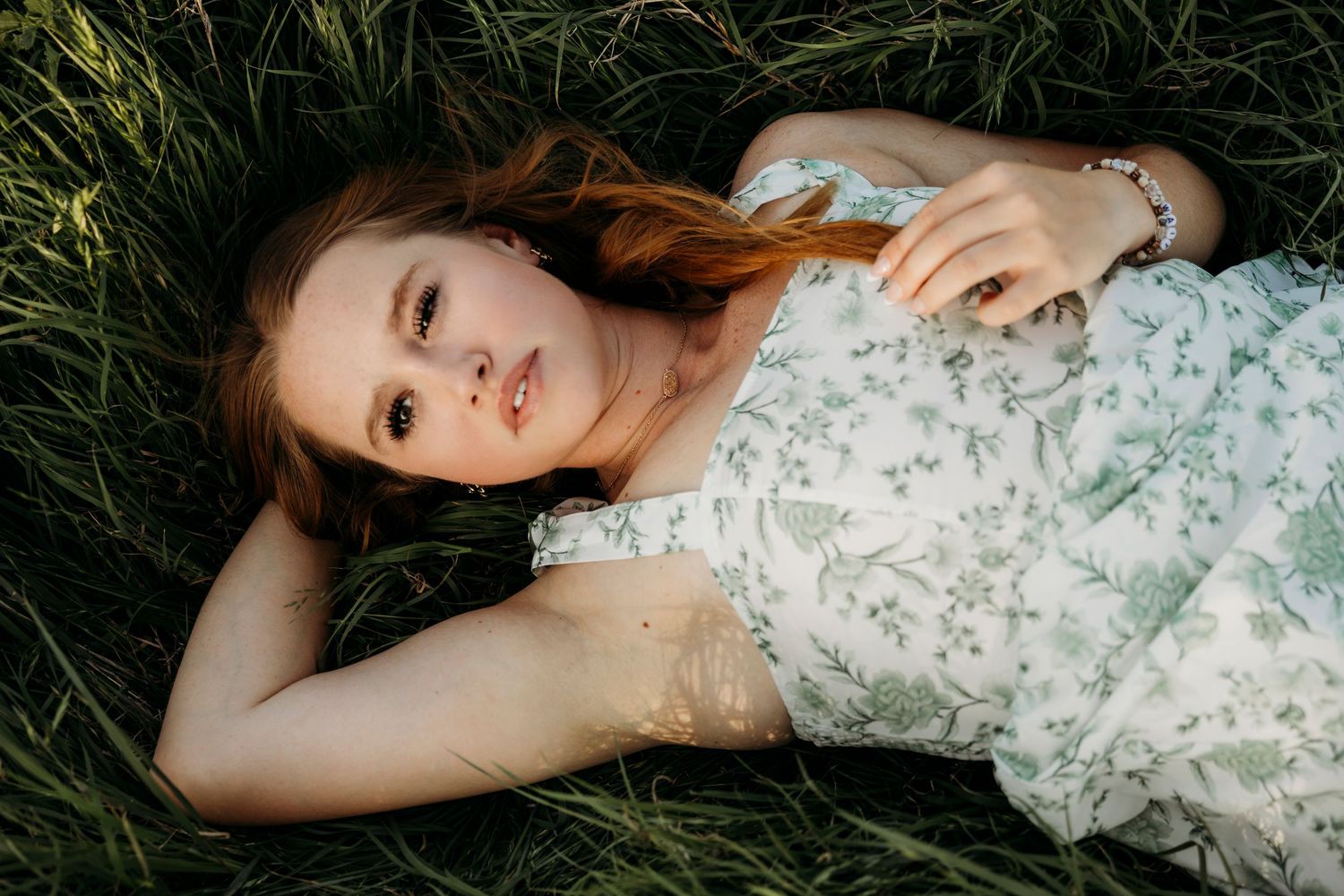 high school senior laying in grass at golden hour