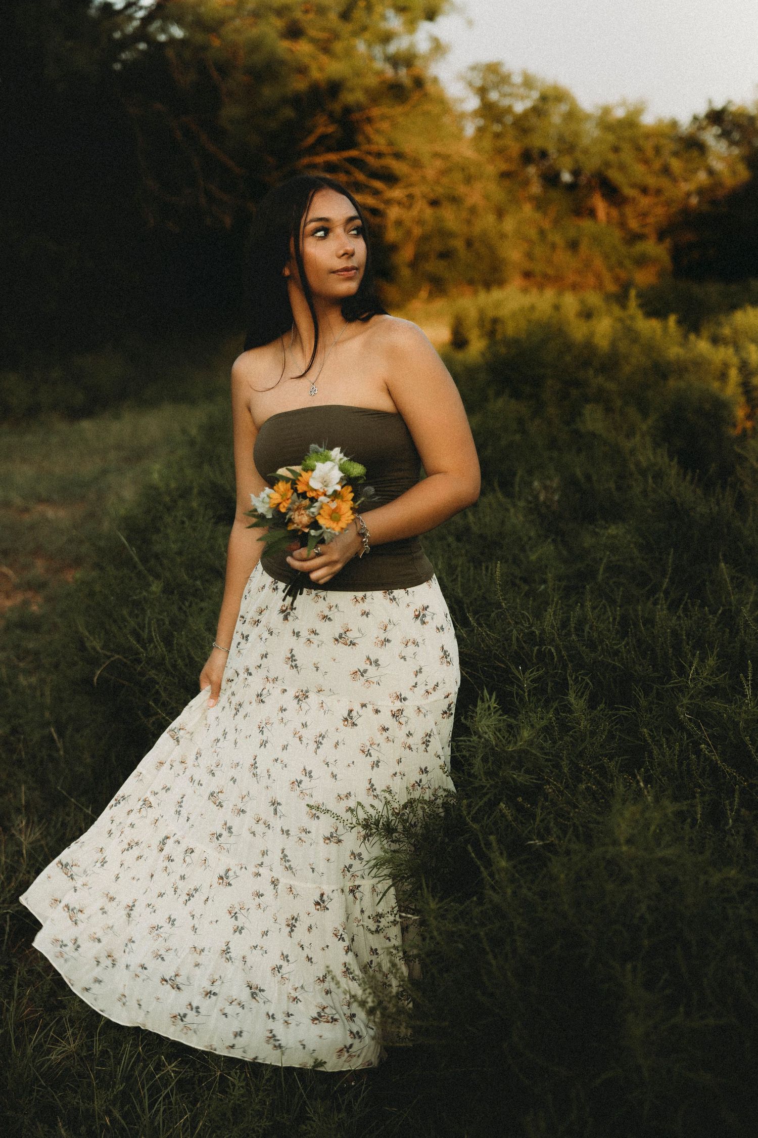 Outdoor senior portrait in a floral dress holding a bouquet during a golden hour session in Abilene, Texas.