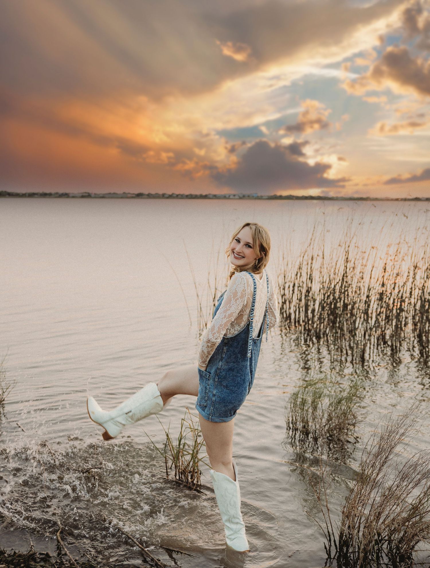 High school senior standing along the lakeshore at sunset during a golden hour senior photography session in Abilene, Texas.