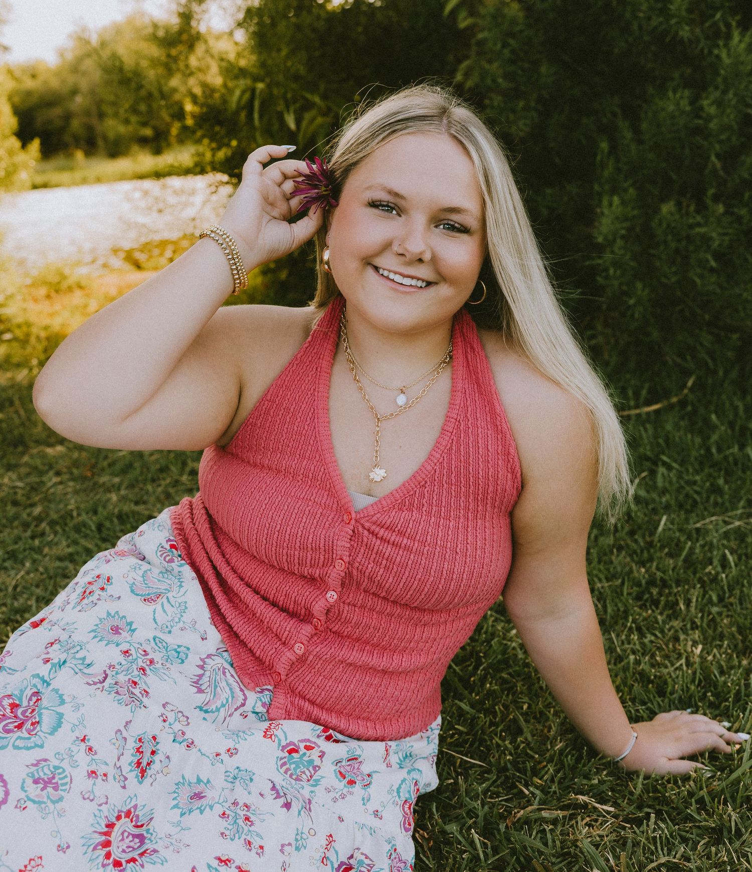 Smiling Wylie High School senior sitting in the grass during a golden hour senior portrait session in Abilene, Texas.