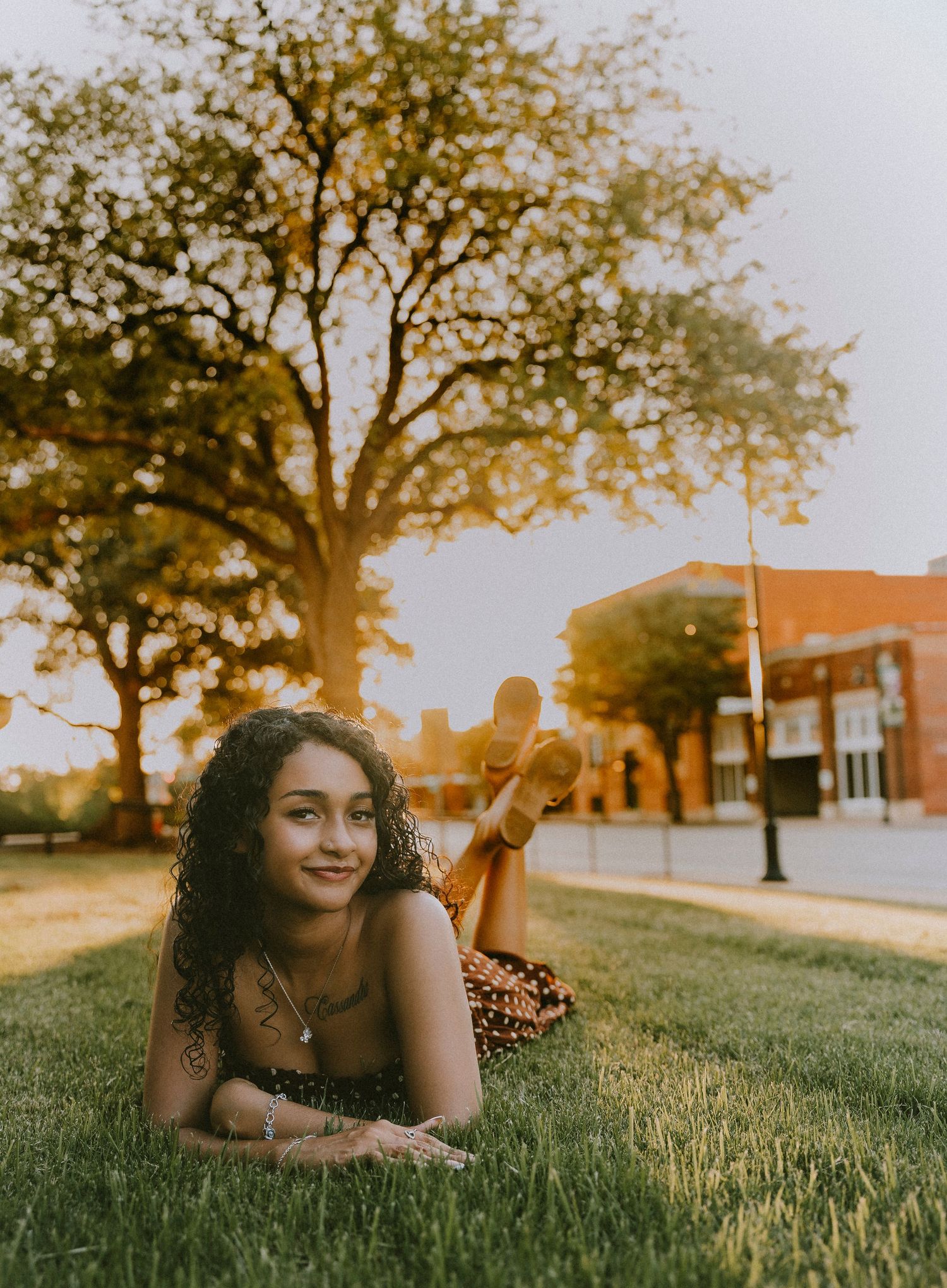 Senior girl lying on a grass in downtown Abilene during a golden hour Cooper High School senior portrait session.