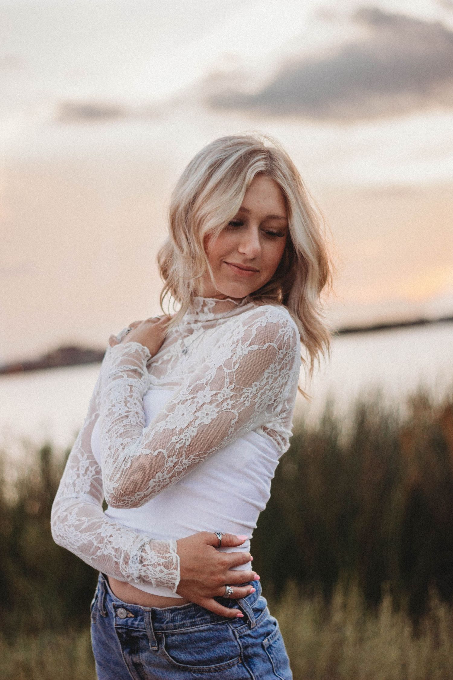 Outdoor senior portrait session in Abilene TX with a high school senior photographed at golden hour in an open field by the lake