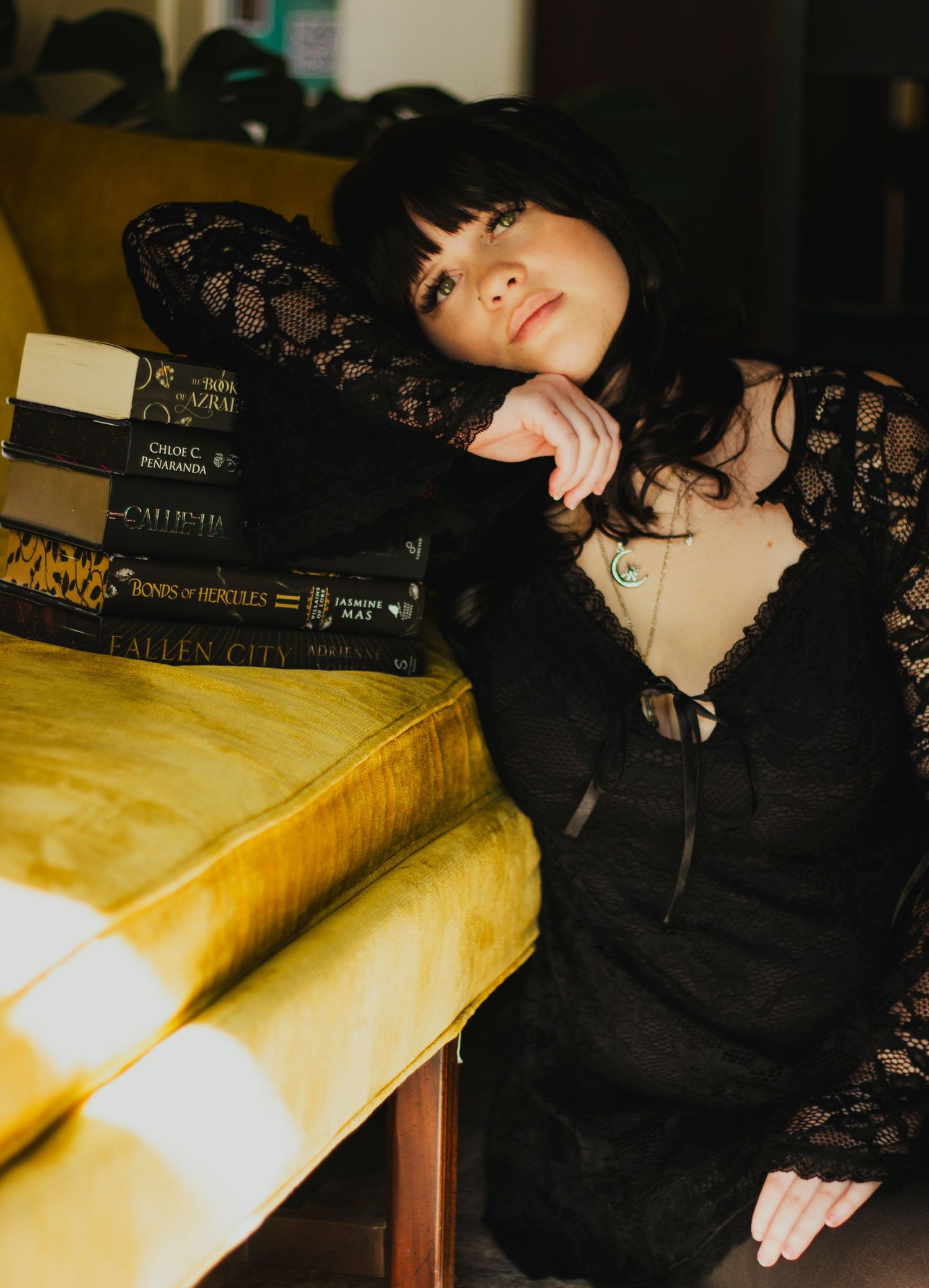 Senior girl  in a black lace dress standing in front of a bookshelf during a moody editorial portrait session.