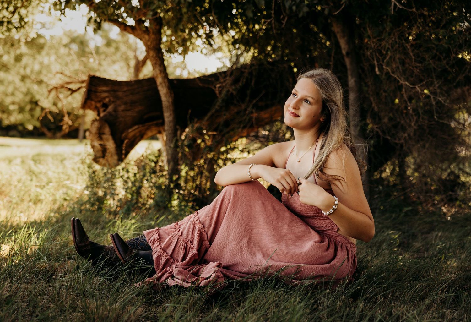 Outdoor senior portrait of a high school senior sitting in a grassy field during a sunset senior photography session in Abilene, Texas.