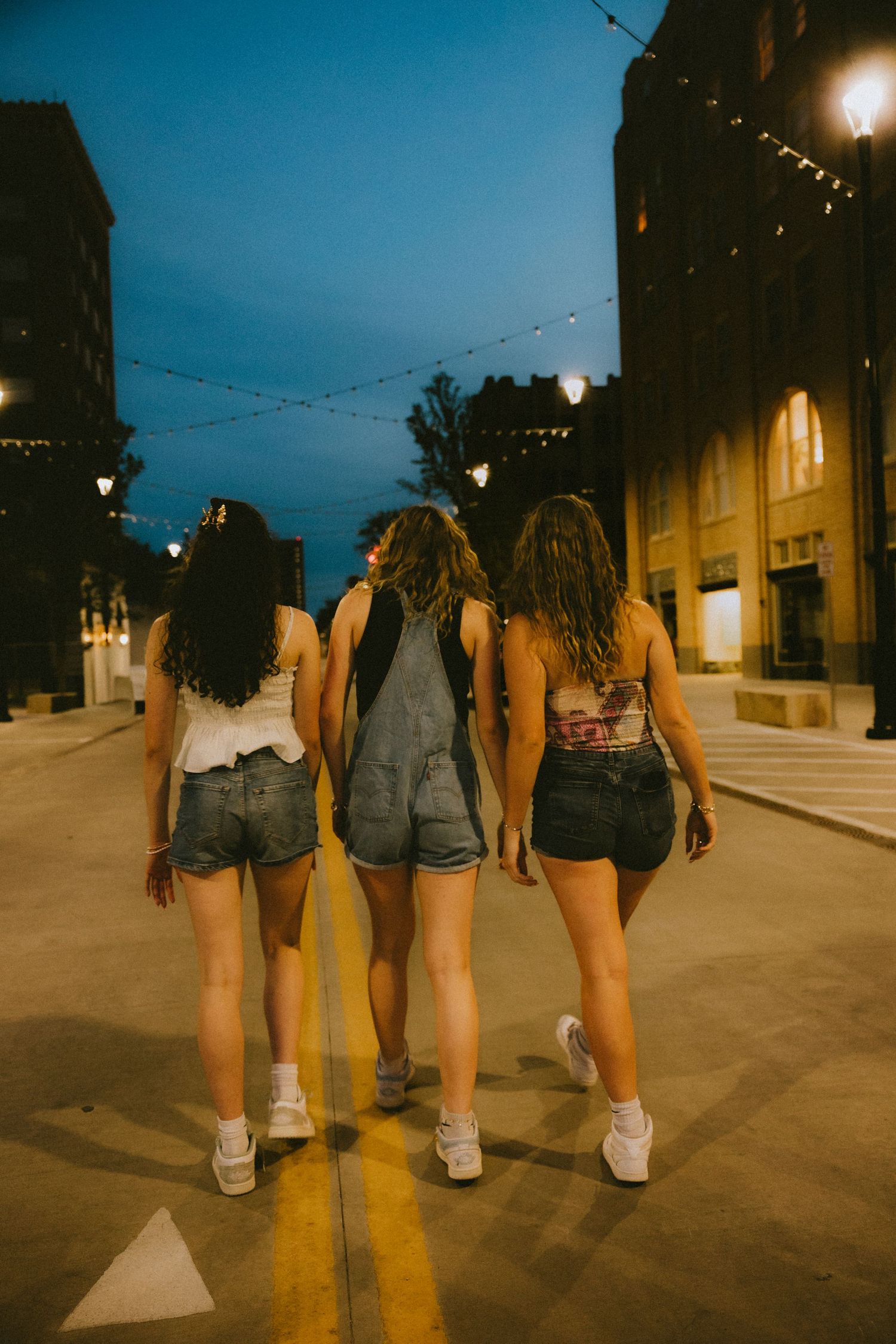 Three best friends walking down a downtown street at dusk in Abilene Texas