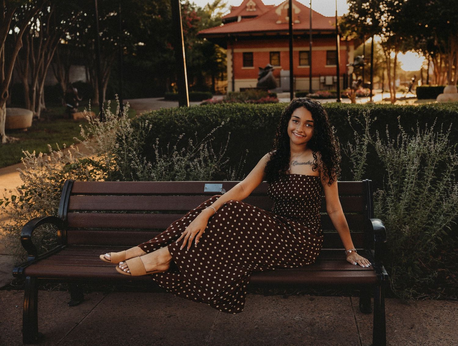 Class of 2027 Cooper High School senior sitting on a downtown Abilene park bench during a warm golden hour portrait session.