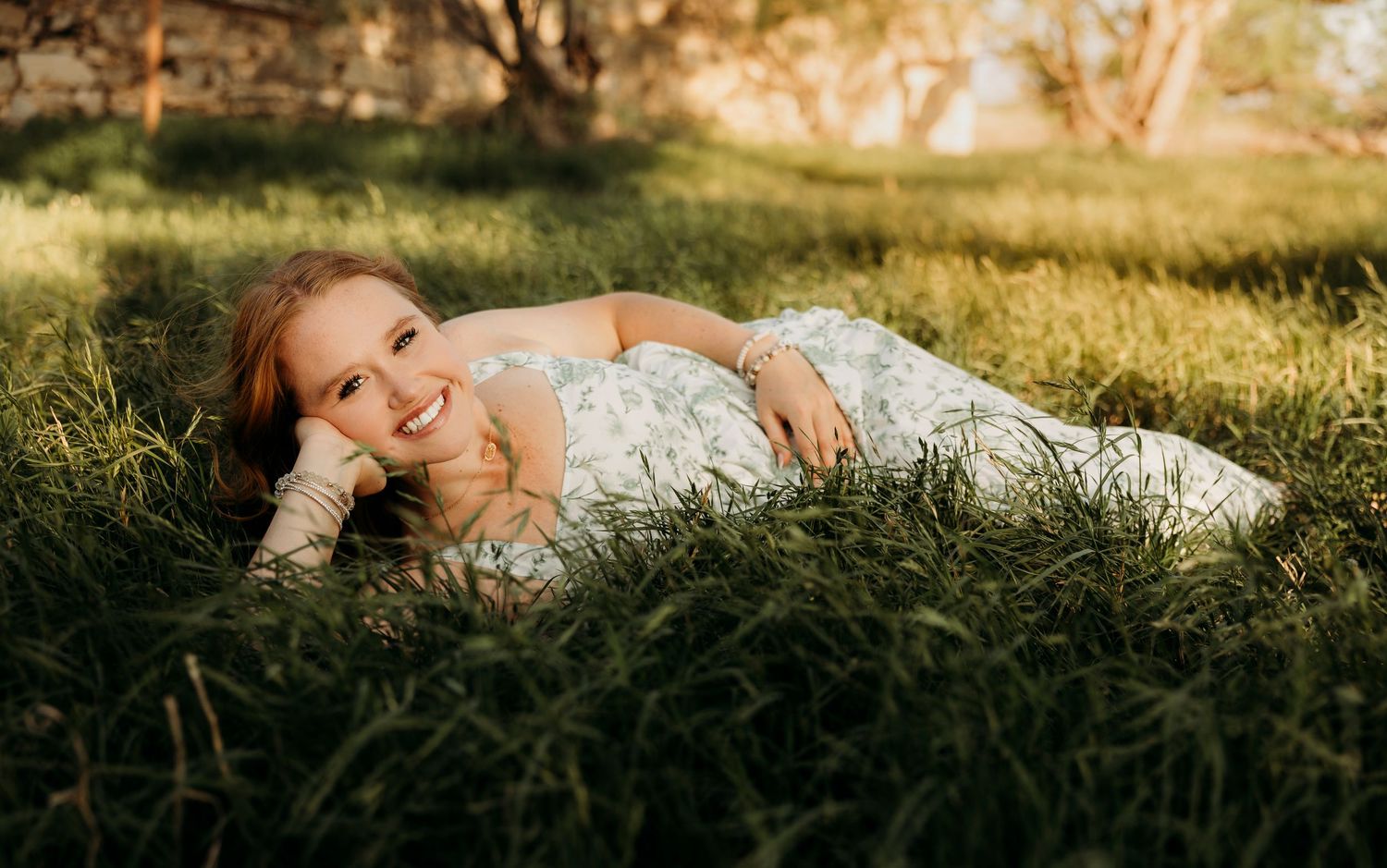 High school senior girl laying in tall grass during a golden hour senior portrait session in Abilene, Texas.