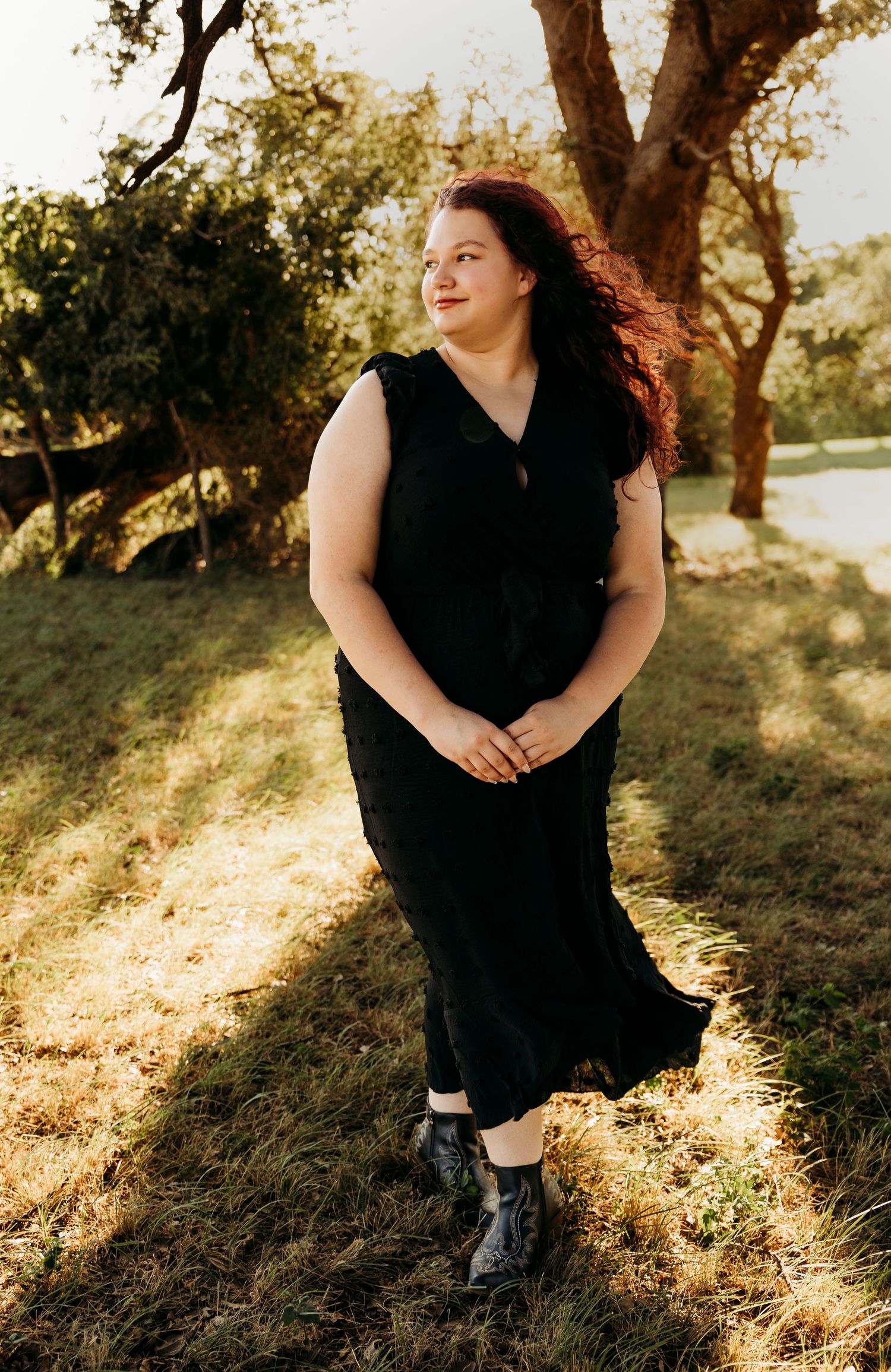 Outdoor senior portraits of a Class of 2027 senior wearing a black dress beneath oak trees during a golden hour senior photos