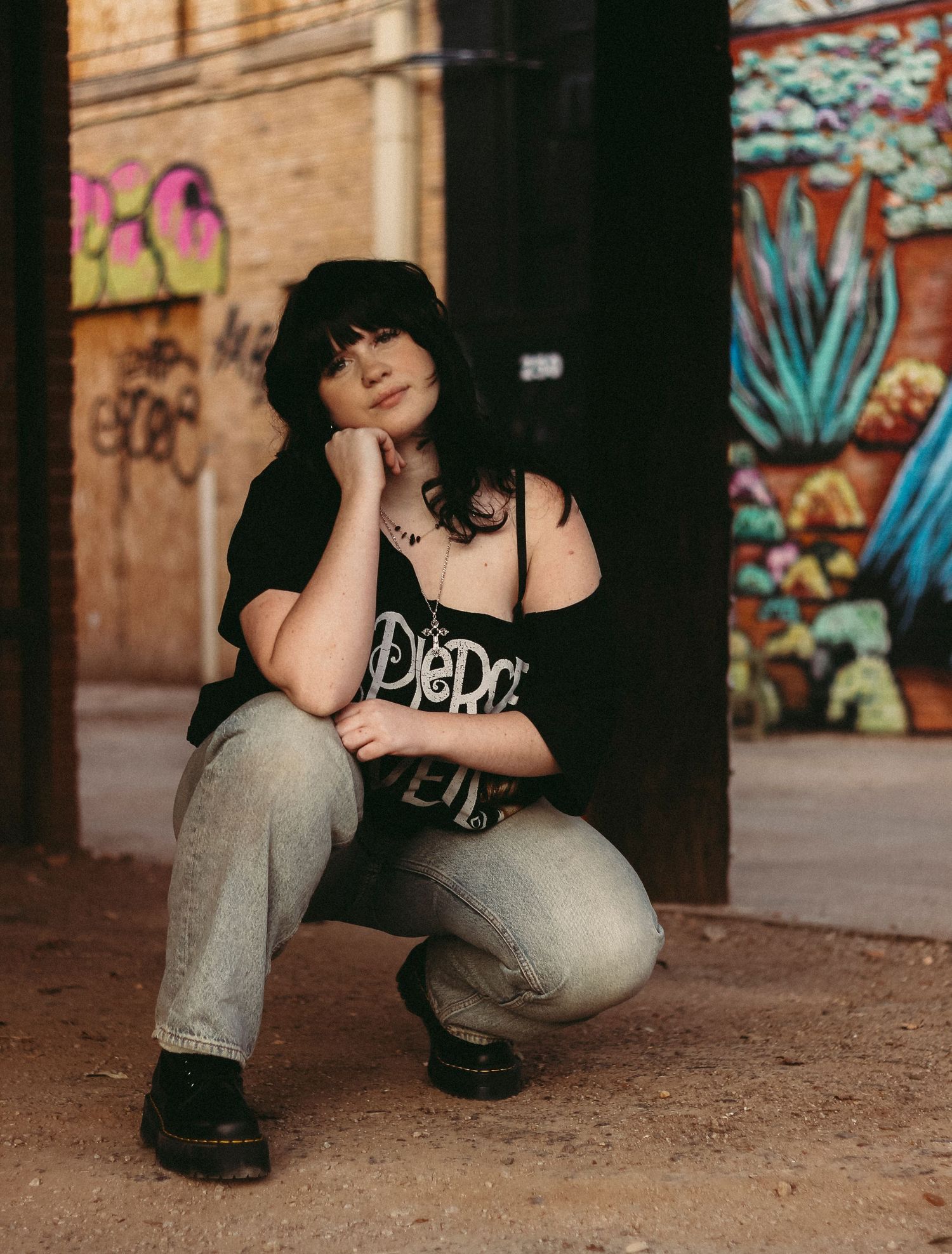 Person in black clothing crouches near graffiti-covered walls in an urban setting, shown in multiple similar poses.