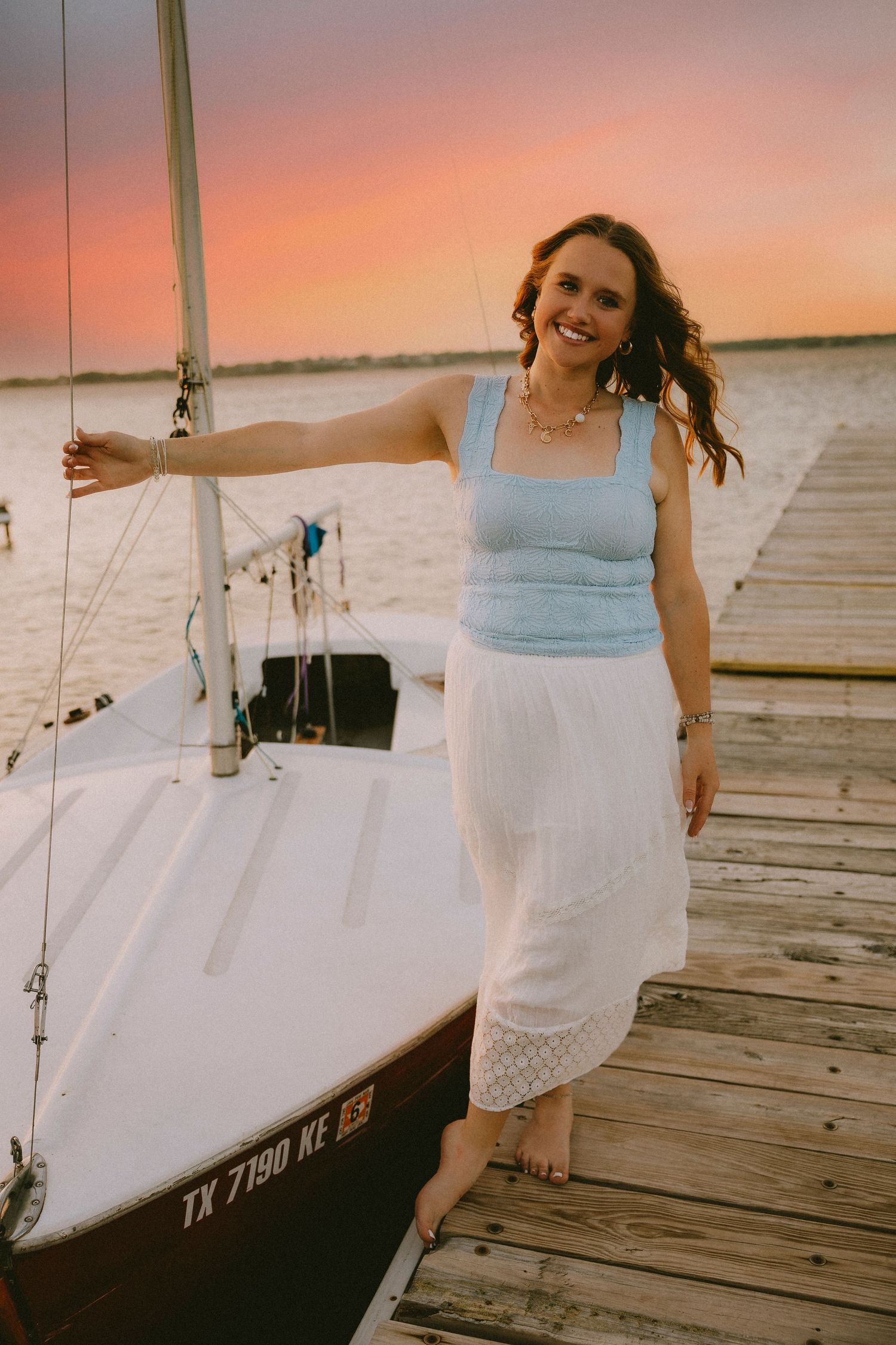 Senior session by the sailboat at sunset in Abilene, TX with soft, dreamy waterfront vibes