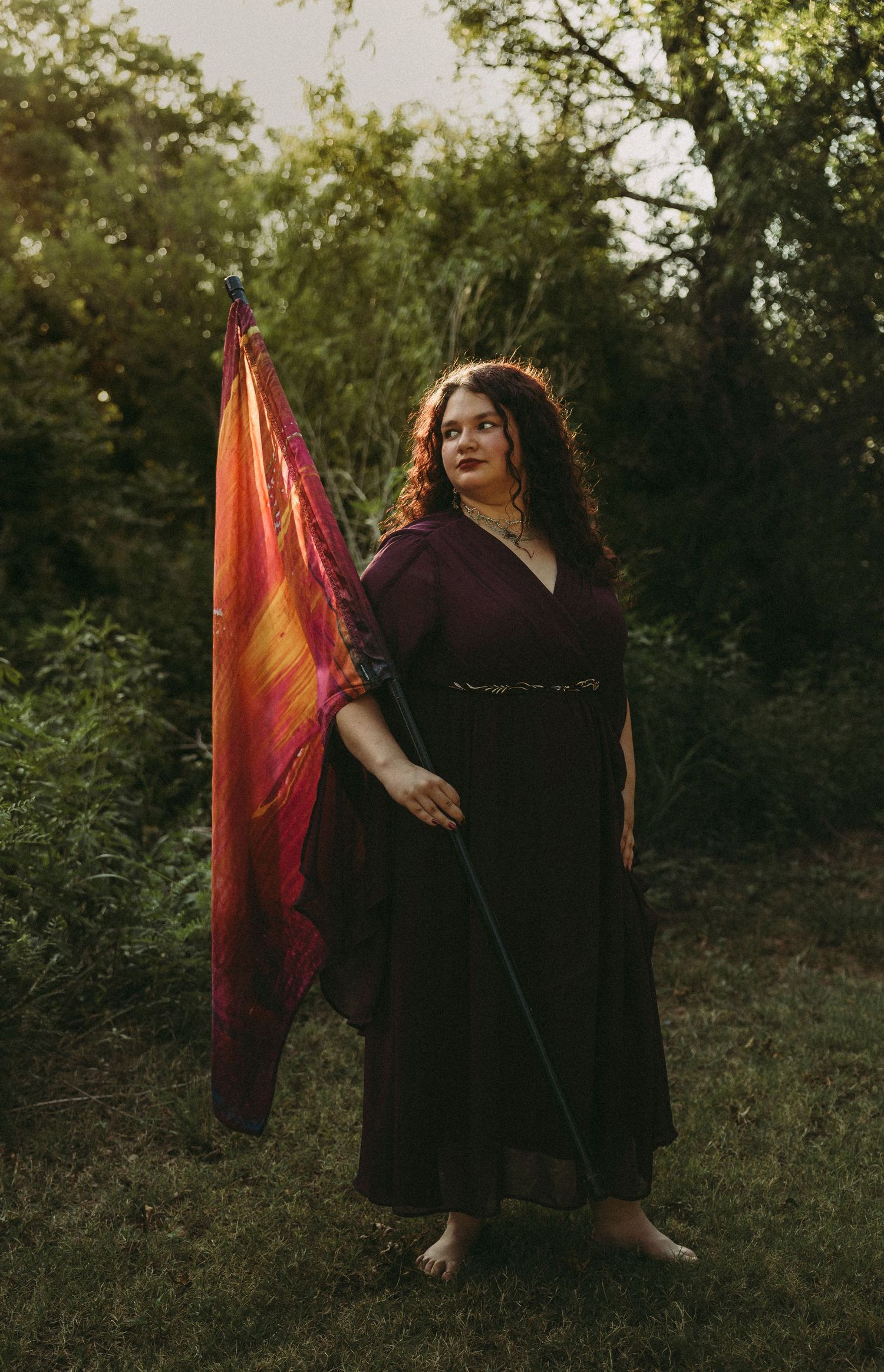 Class of 2027 Jim Ned High School color guard senior posing with her flag during an outdoor senior photography session in Abilene, Texas.