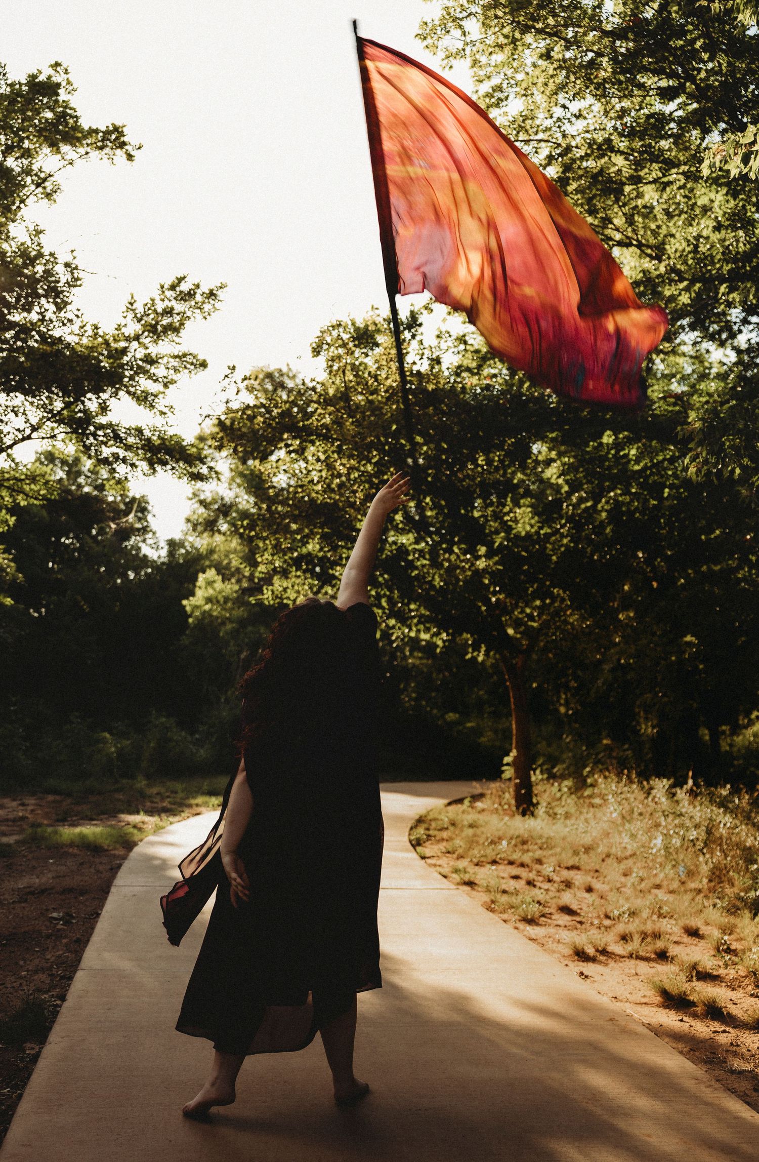 Jim Ned High School color guard senior holding a vibrant color guard flag during a golden hour senior portrait session in Abilene, Texas.