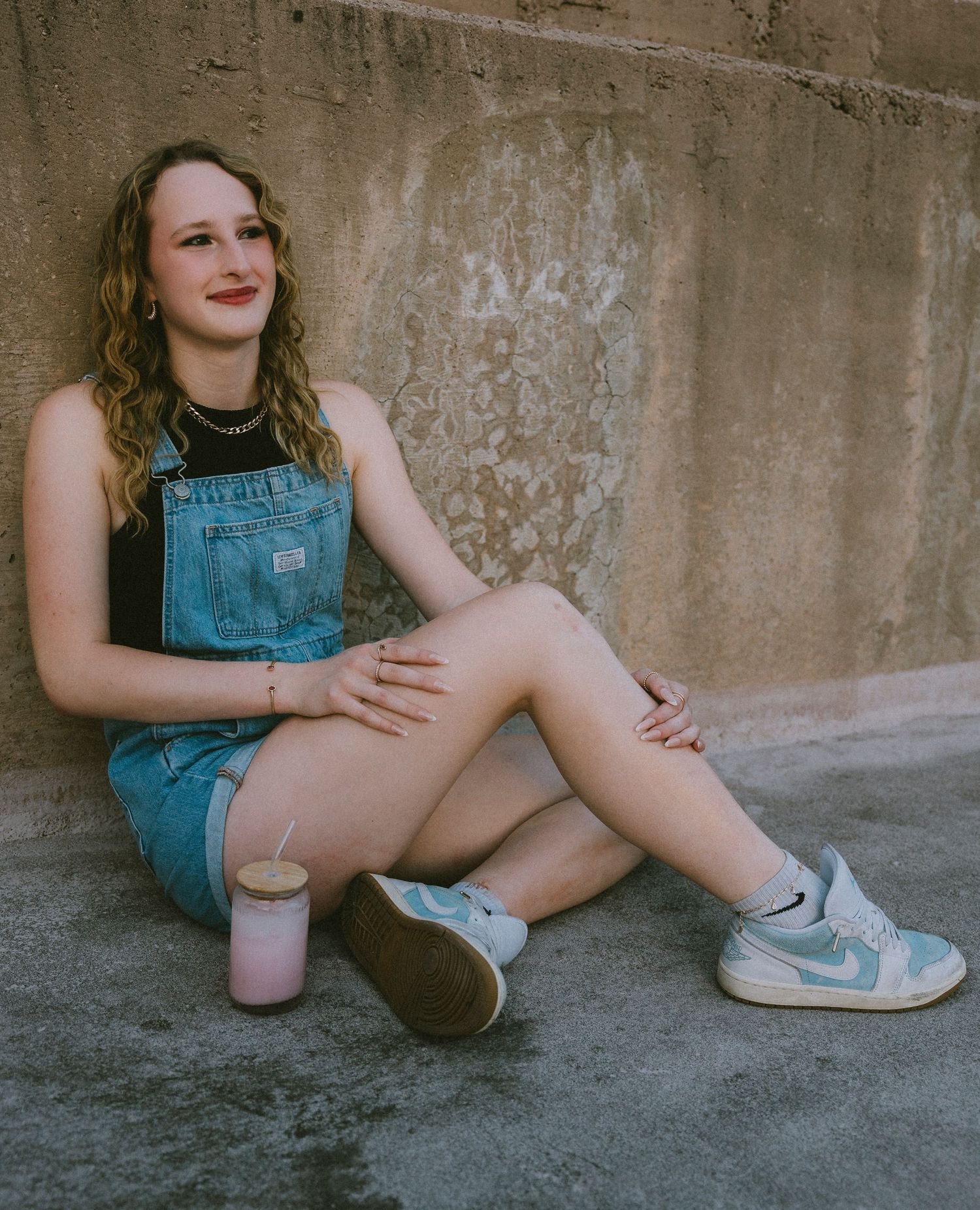 Urban senior portrait of a high school senior sitting against a concrete wall during a modern senior photography session in Abilene, Texas.