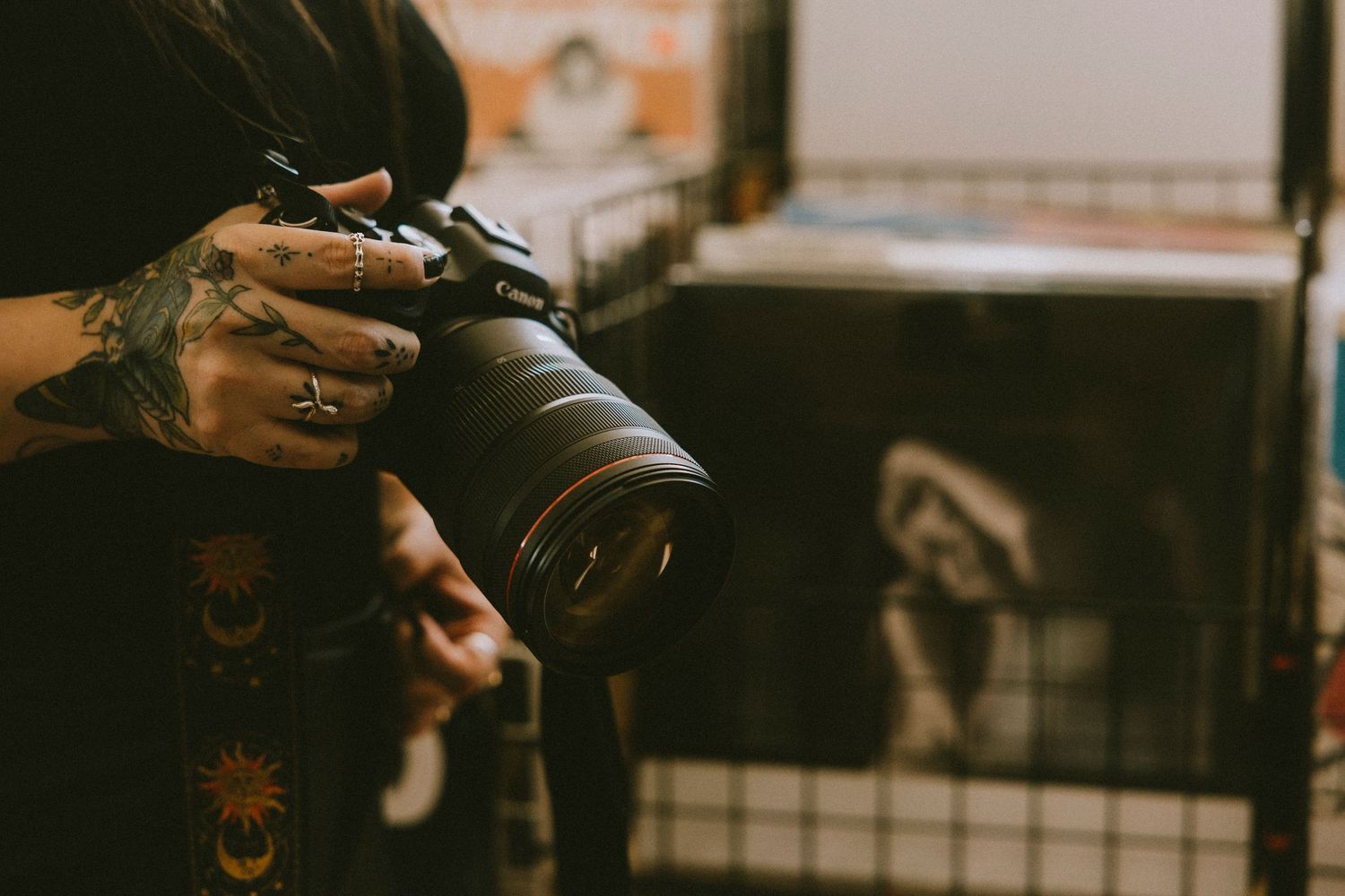 Close-up of photographer holding camera in a moody creative workspace, showcasing photography tools and behind-the-scenes artistry.