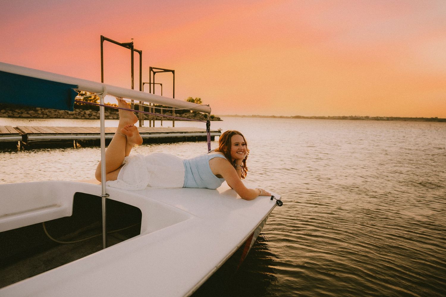 Senior portrait on sailboat at sunset during lake session in Abilene Texas