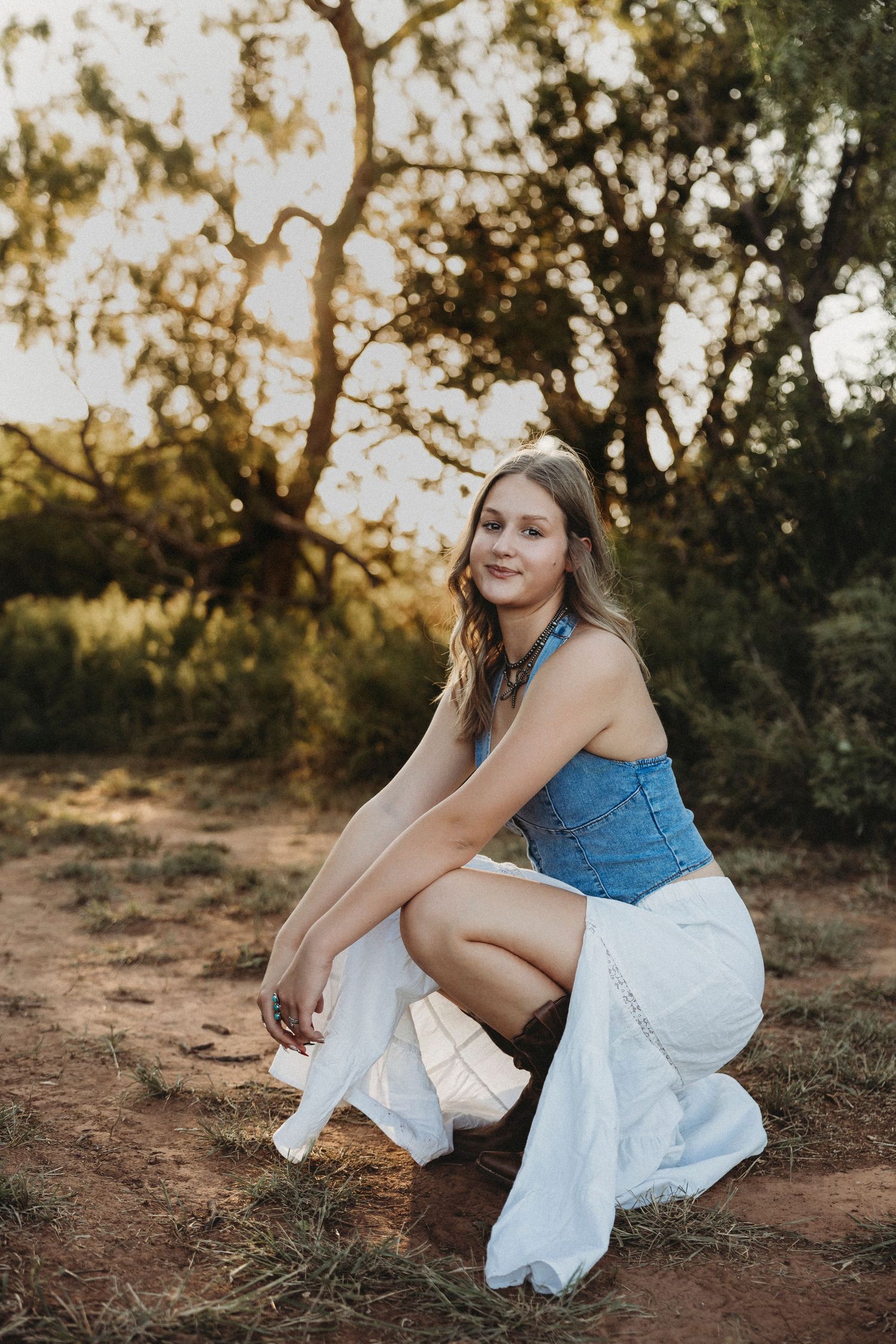 High school senior rep smiling in a western-inspired outfit during a golden hour senior portrait session in Buffalo Gap, Texas.