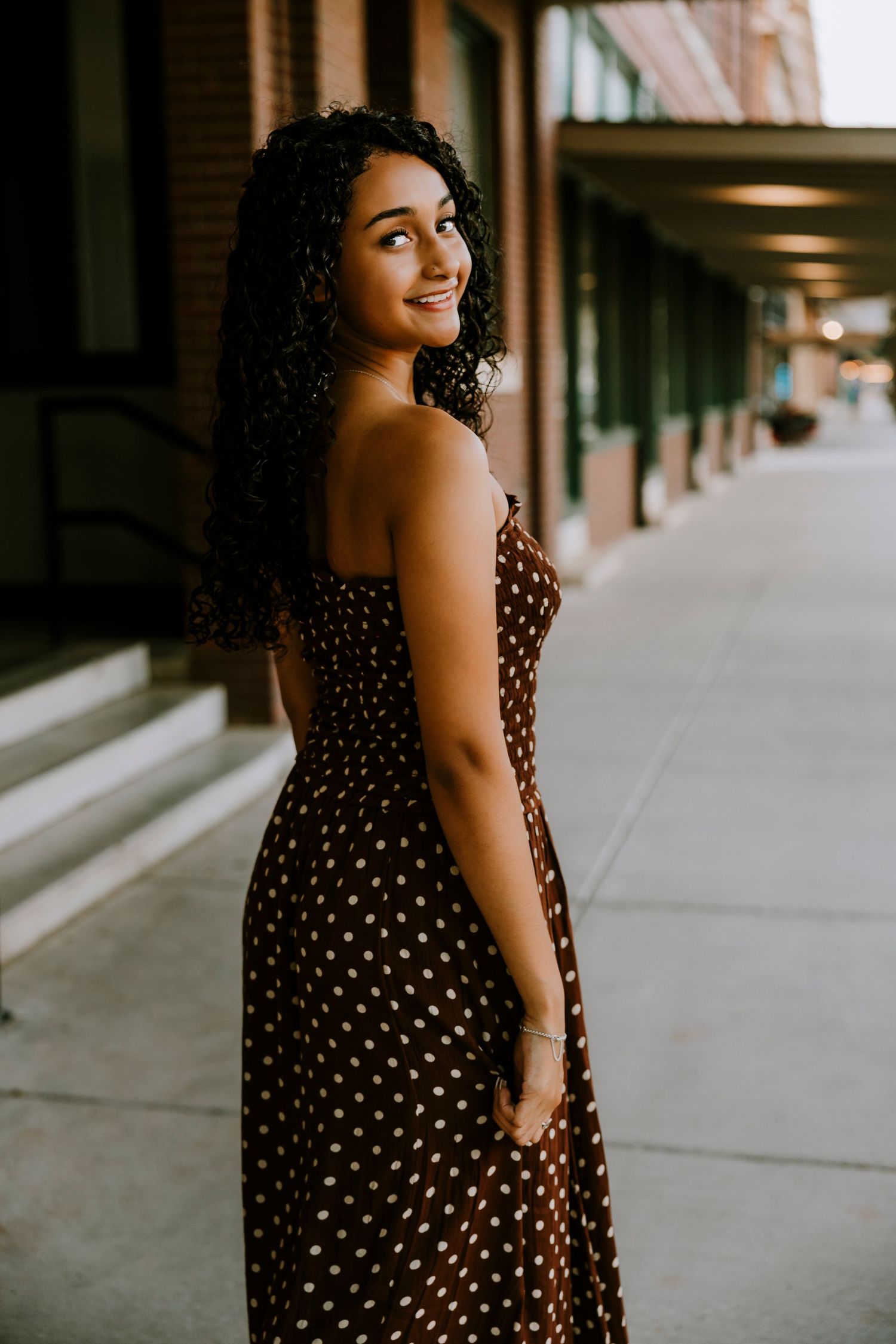 Cooper High School senior smiling over her shoulder in downtown Abilene, Texas during a golden hour senior portrait session.