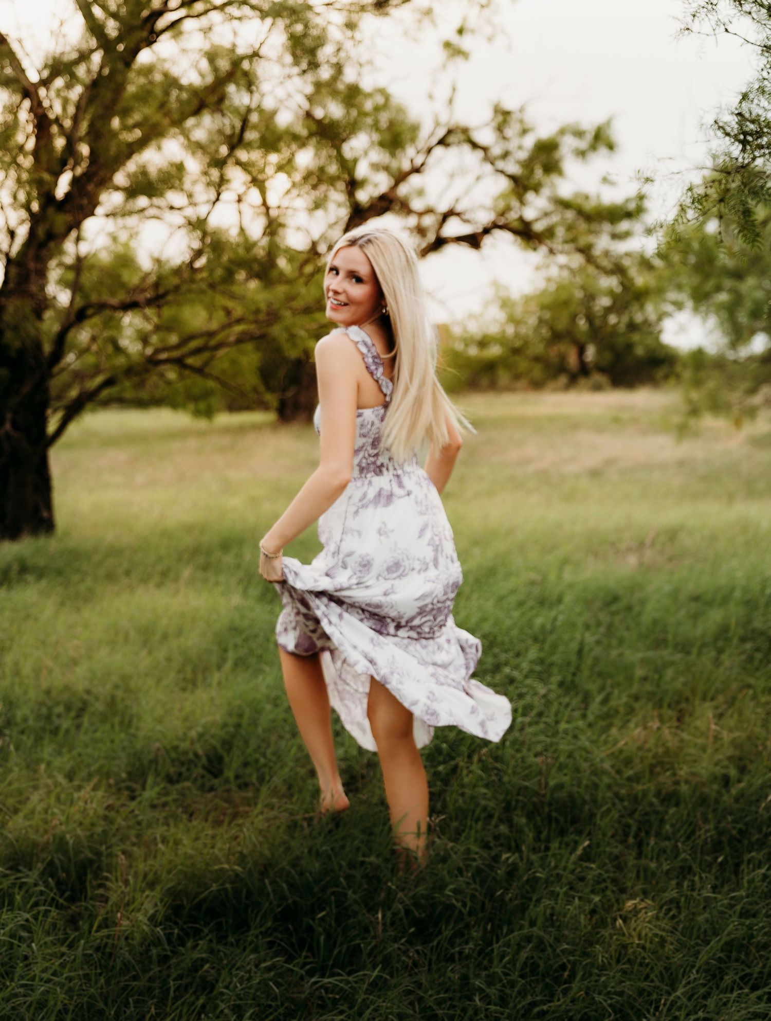 Senior girl in flowing white dress during golden hour field session in Abilene TX