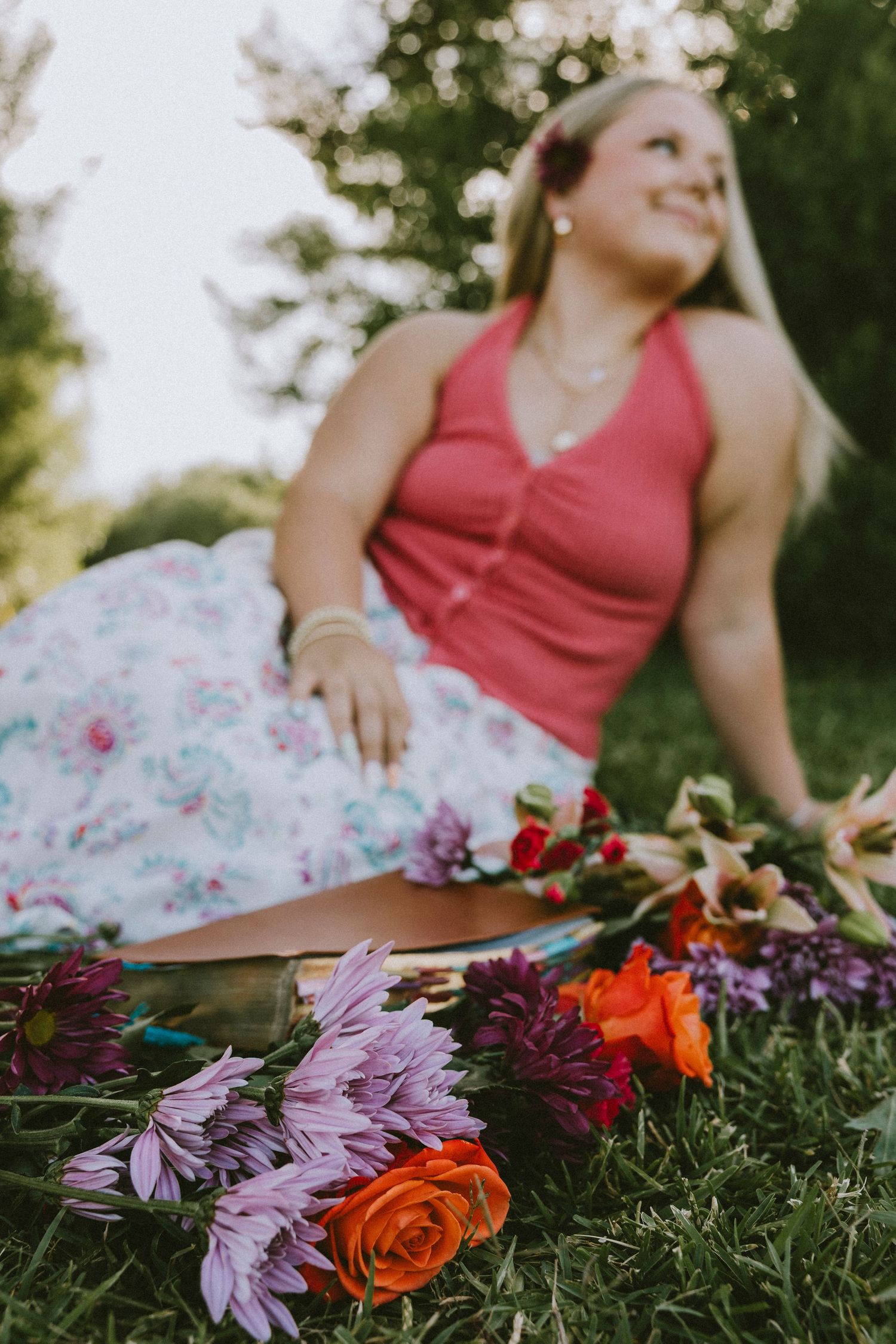 Outdoor senior portrait of a Wylie High School senior sitting among vibrant flowers during a golden hour senior photography session in Abile