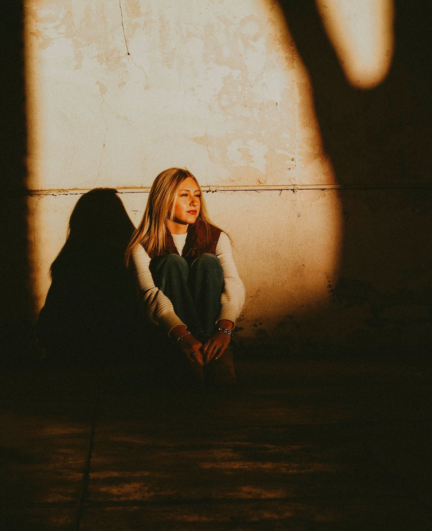 Moody senior portrait session in Abilene TX featuring a high school senior posed against a wall with dramatic natural light and shadows