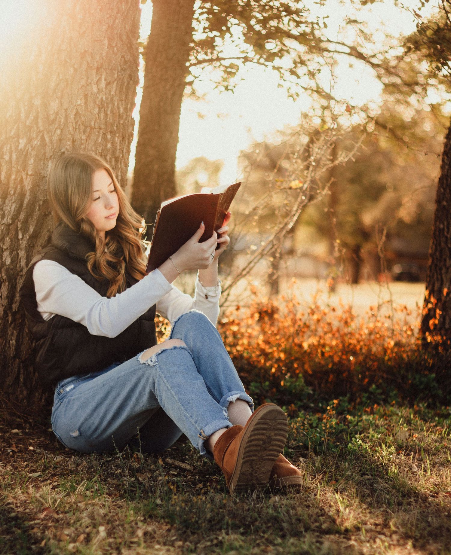 Senior girl reading bible during outdoor golden hour senior photos in Texas