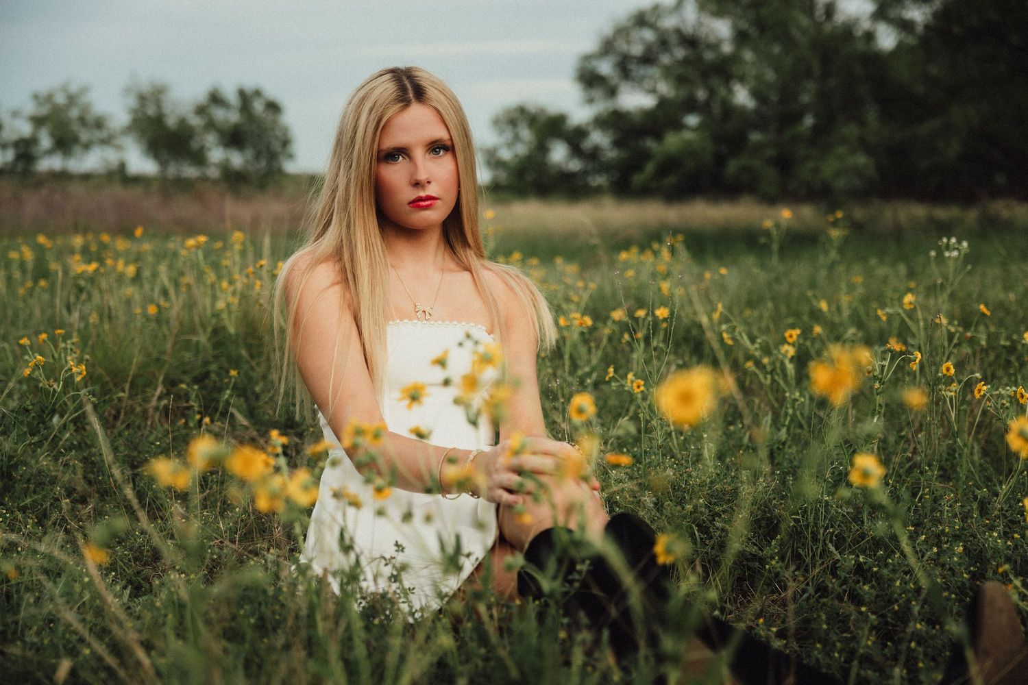 Senior girl sitting in a wildflower field during outdoor senior photos in Abilene, TX